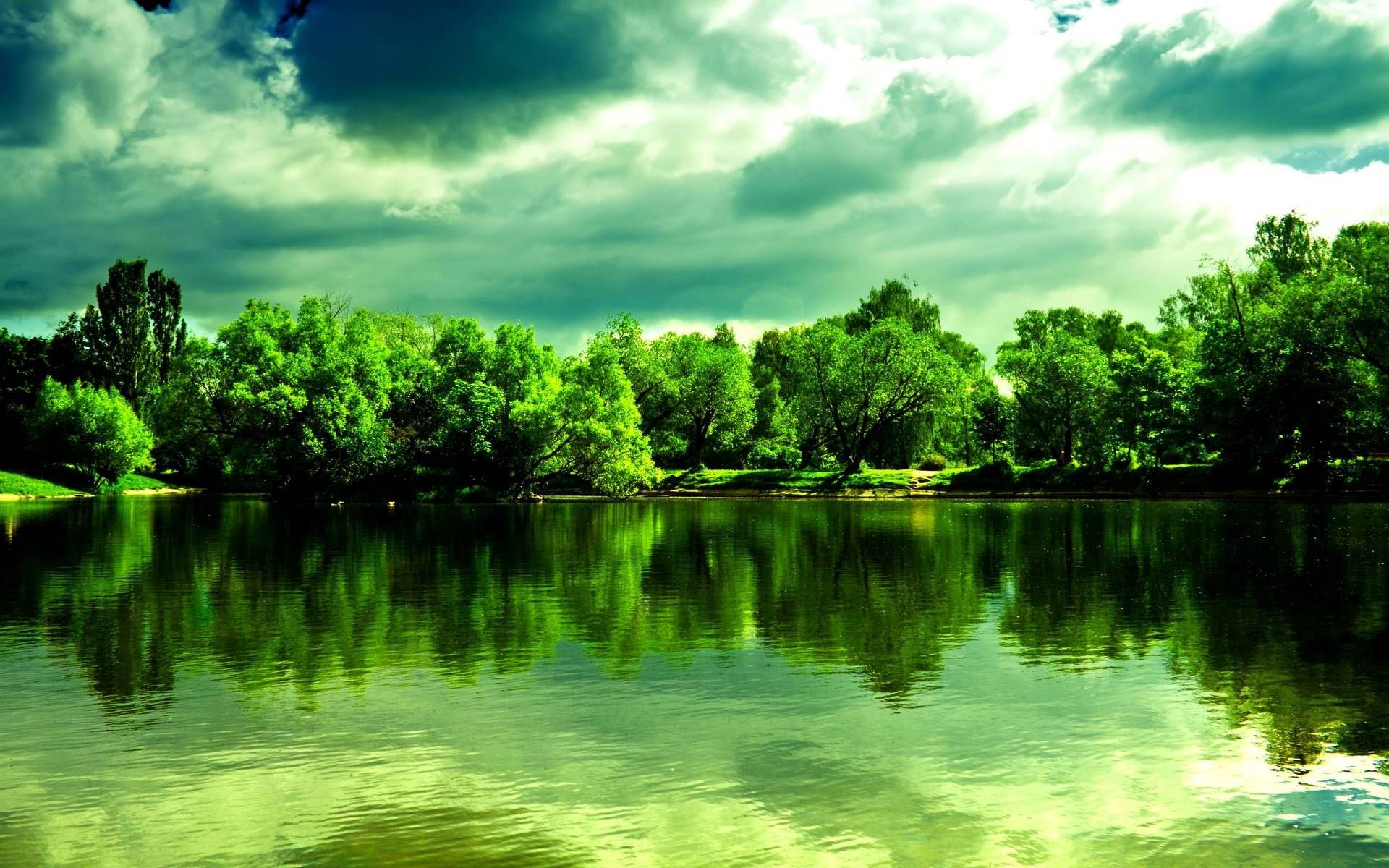 A lake with green trees and clouds in the background - Lake