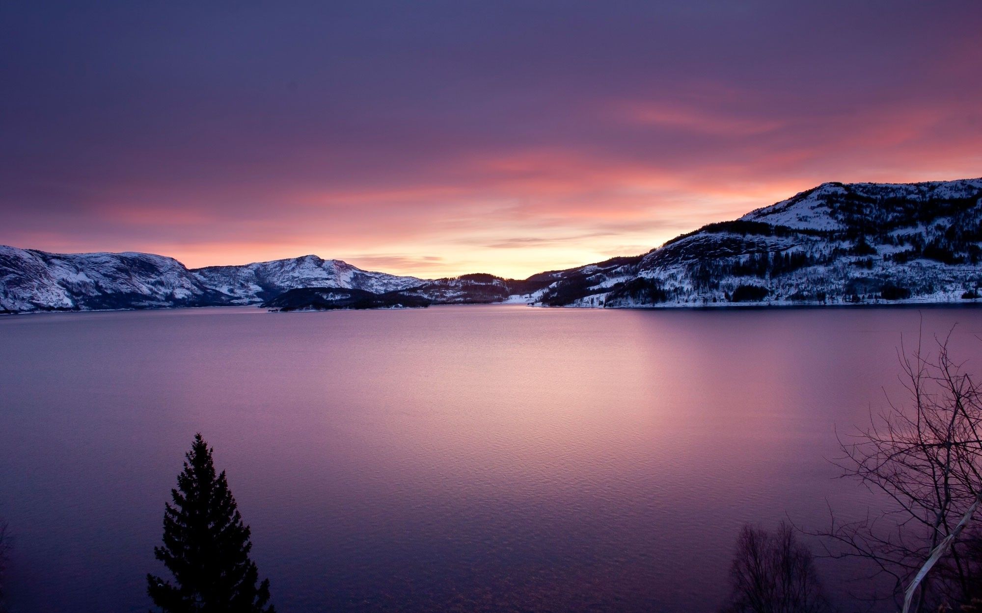 A pink and purple sunset over a lake surrounded by snow covered mountains - Lake