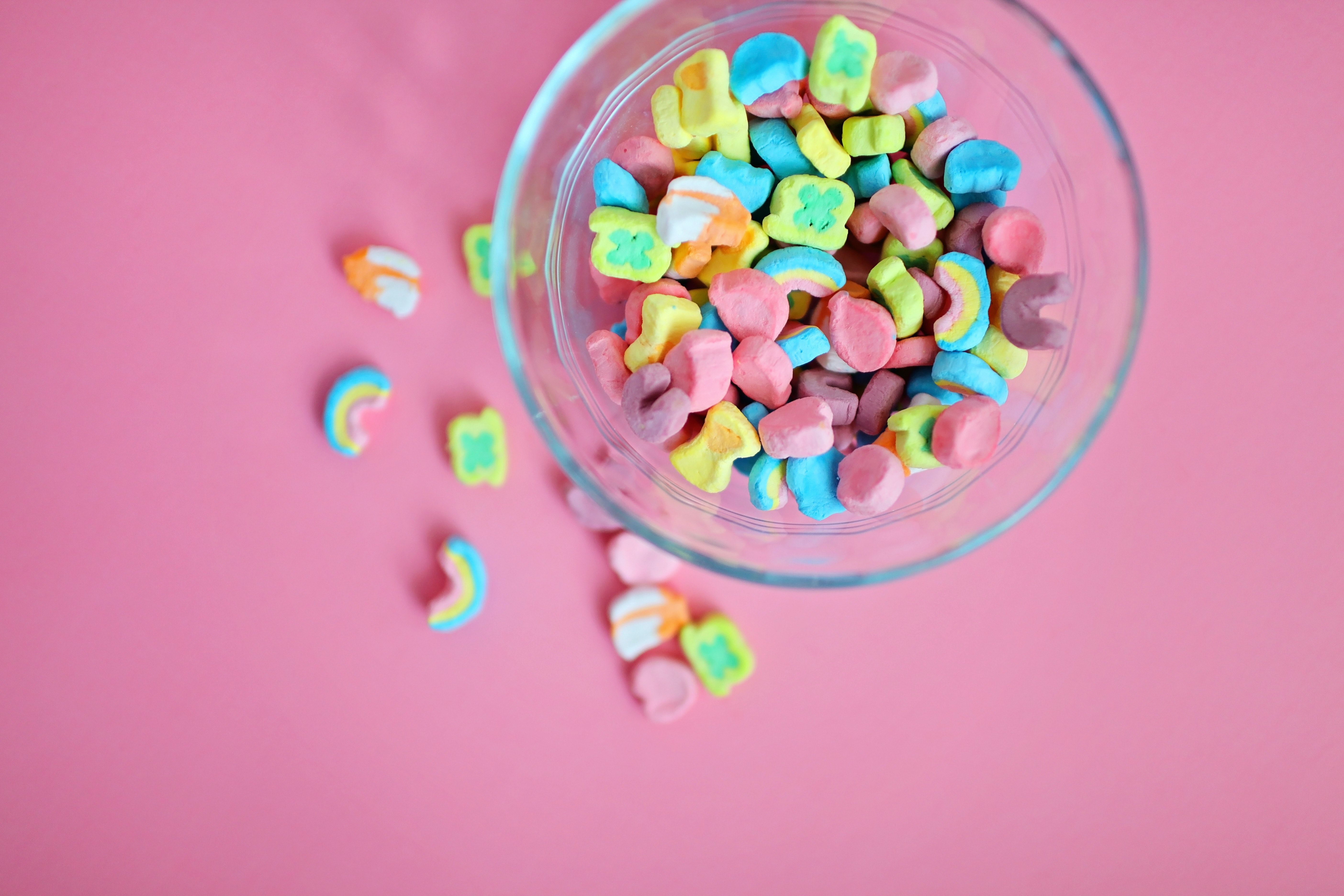 A glass bowl of marshmallows on a pink background. - Candy