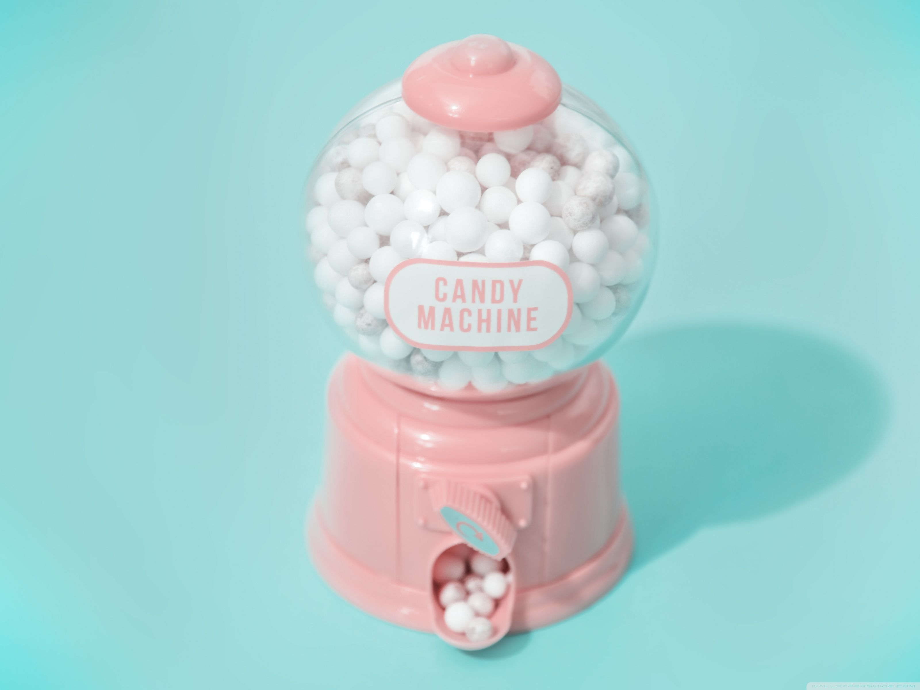 A pink candy machine with white balls inside - Marshmallows