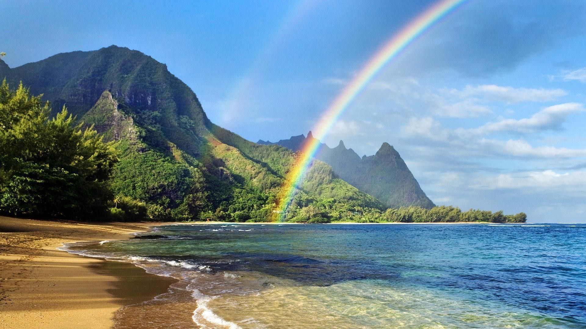 A rainbow over the ocean with mountains in the background - Hawaii