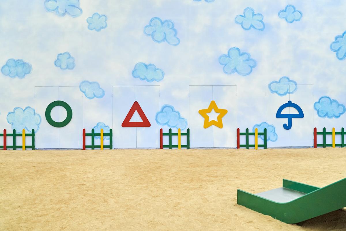 A slide is in the sand next to some walls - Squid Game