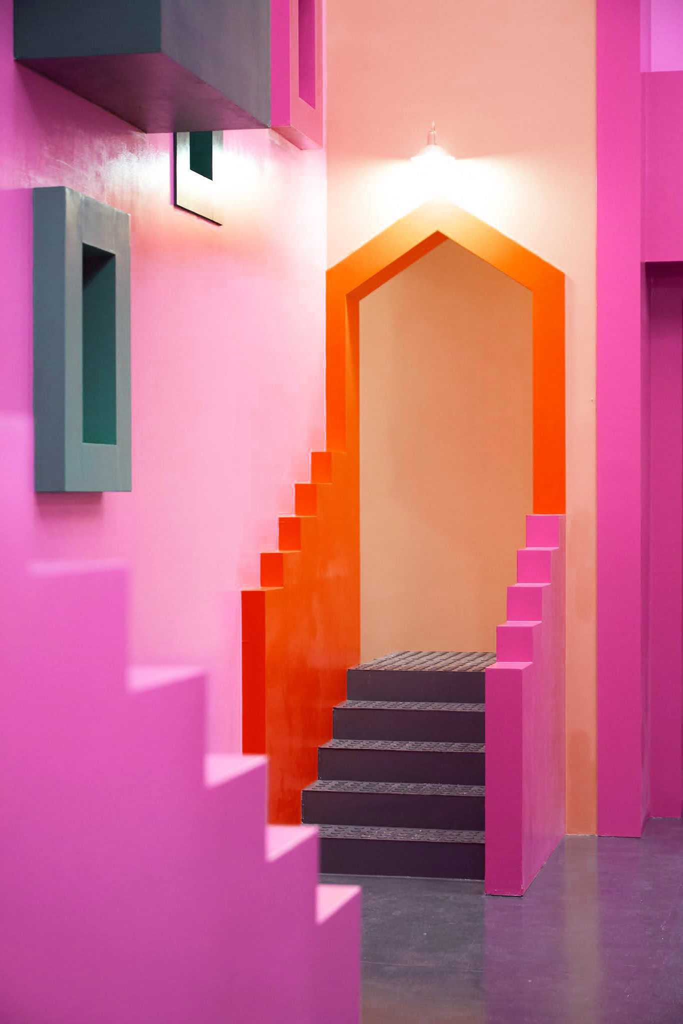 A staircase in a pink building with orange and green walls - Squid Game