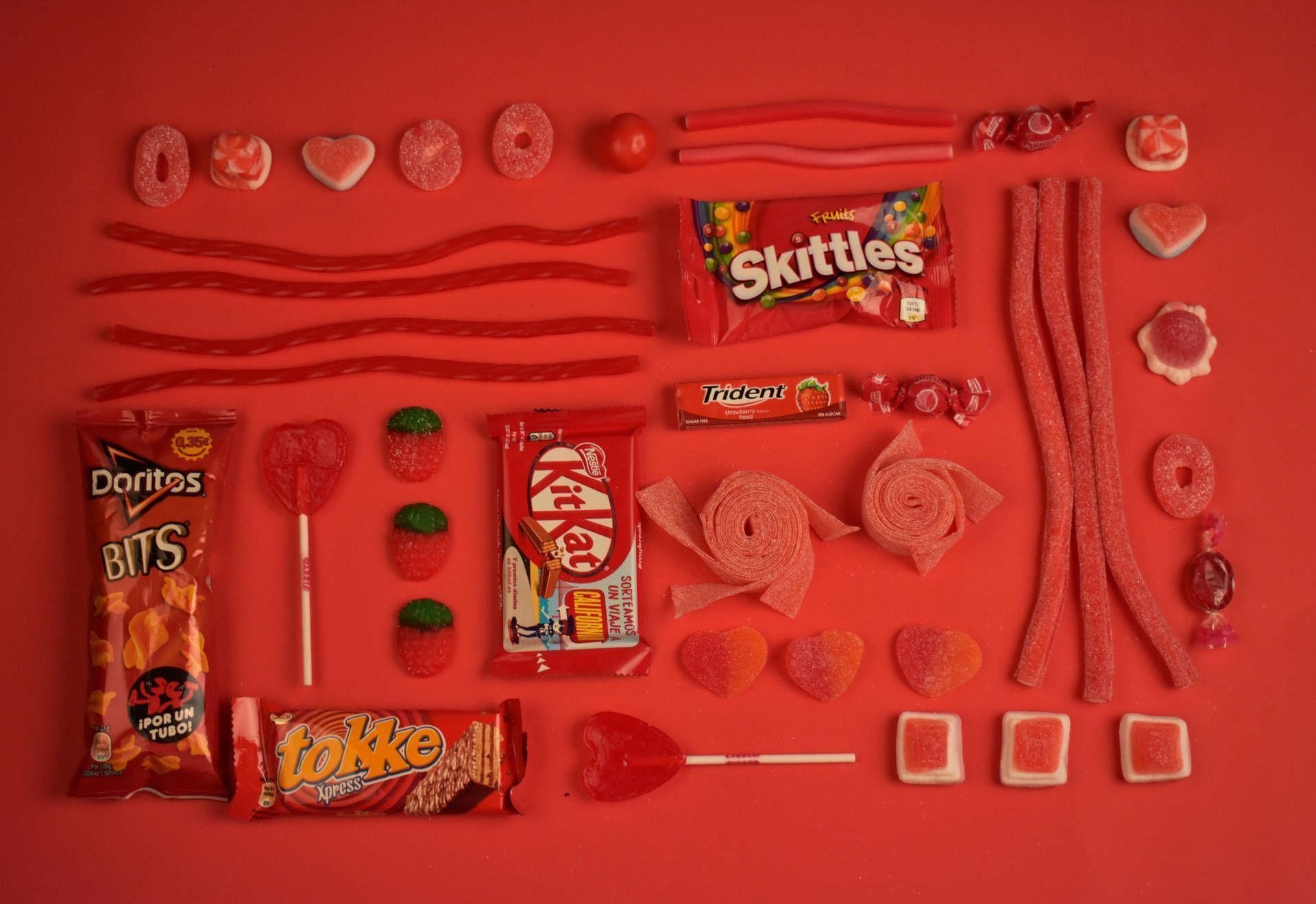 A flat lay of candy against a red background - Doritos