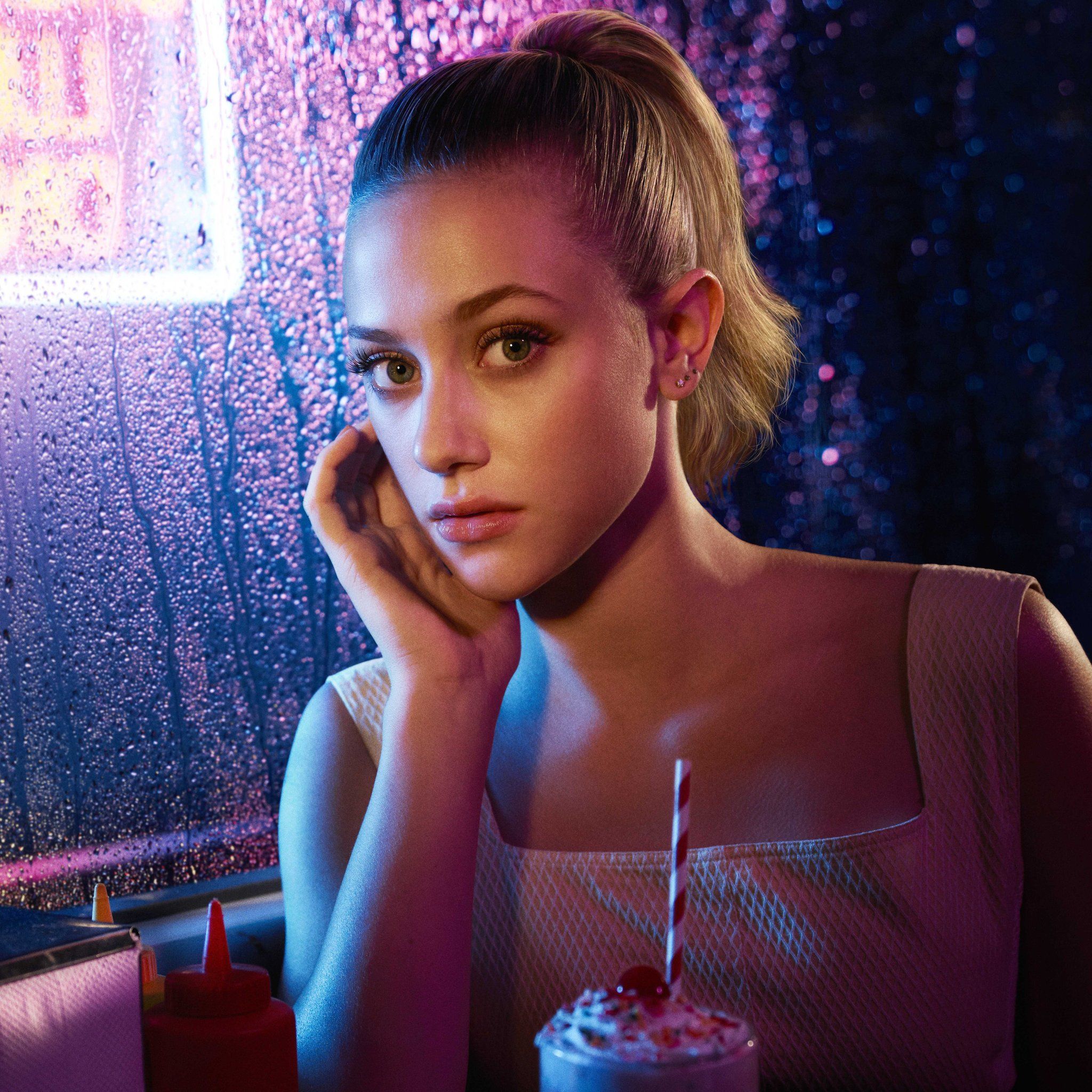 Lili Reinhart sitting at a booth in a diner with a milkshake in front of her - Riverdale