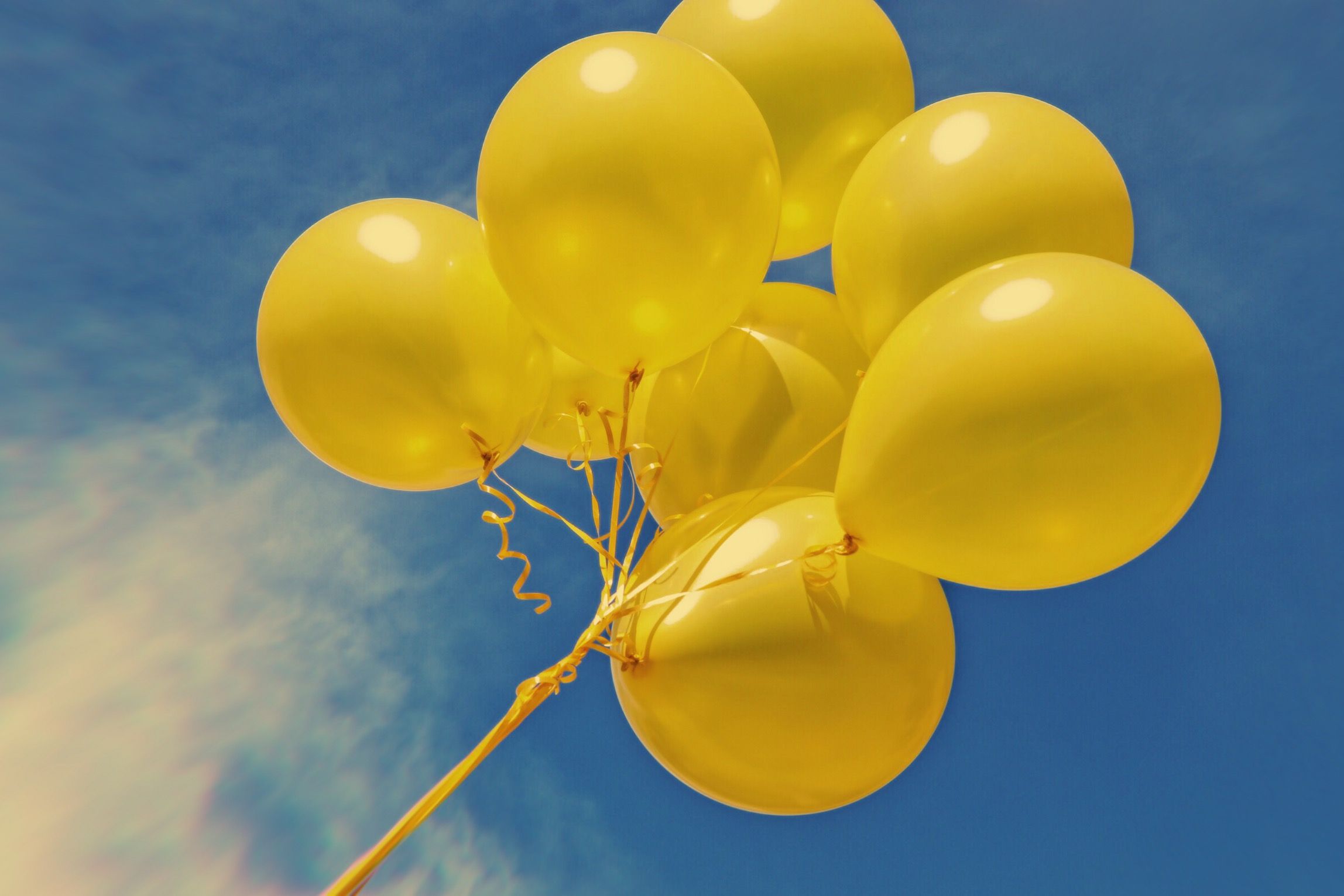 A bunch of yellow balloons float in the sky. - Balloons