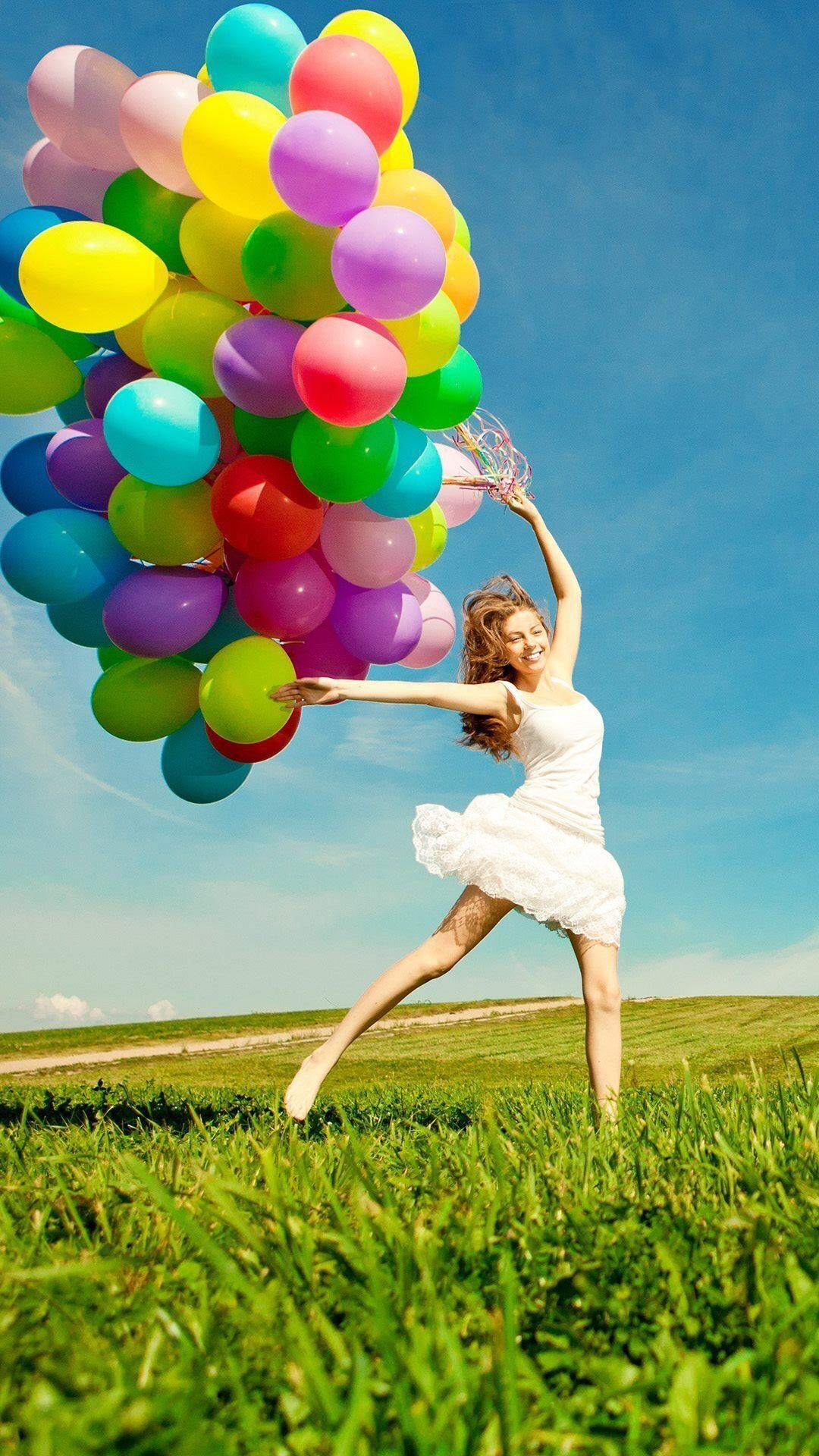 A woman is holding up many colorful balloons - Balloons