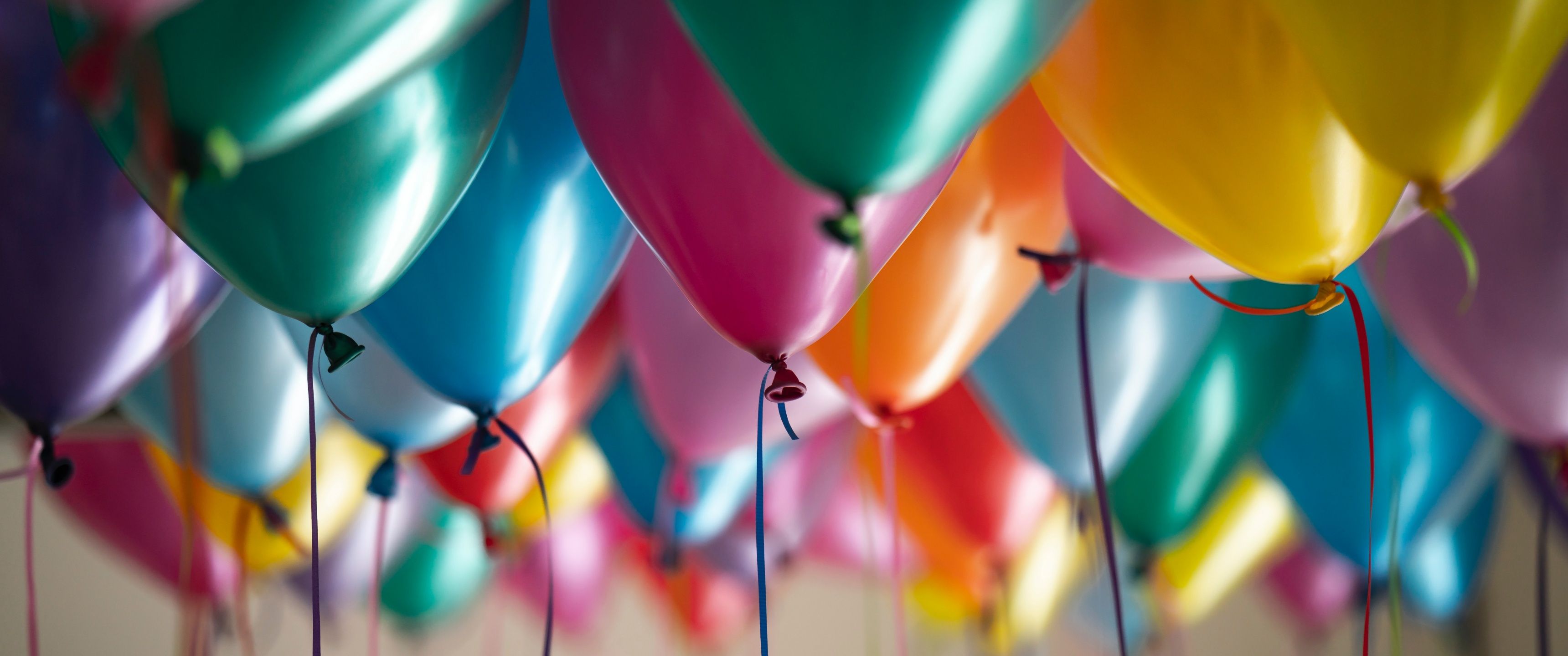 A room full of colorful balloons tied to ribbons. - Balloons