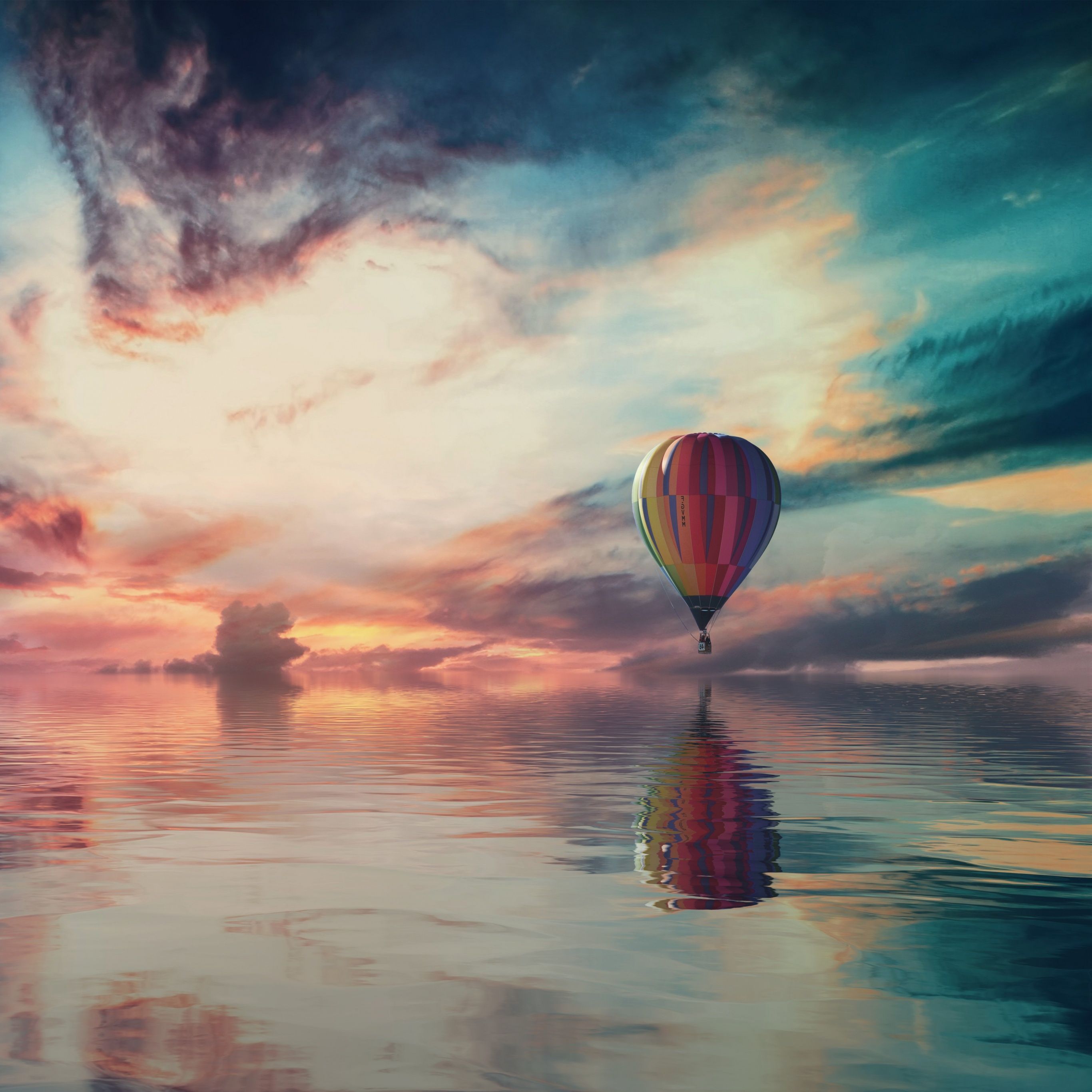 A hot air balloon floating over a body of water with a sunset in the background - Hot air balloons