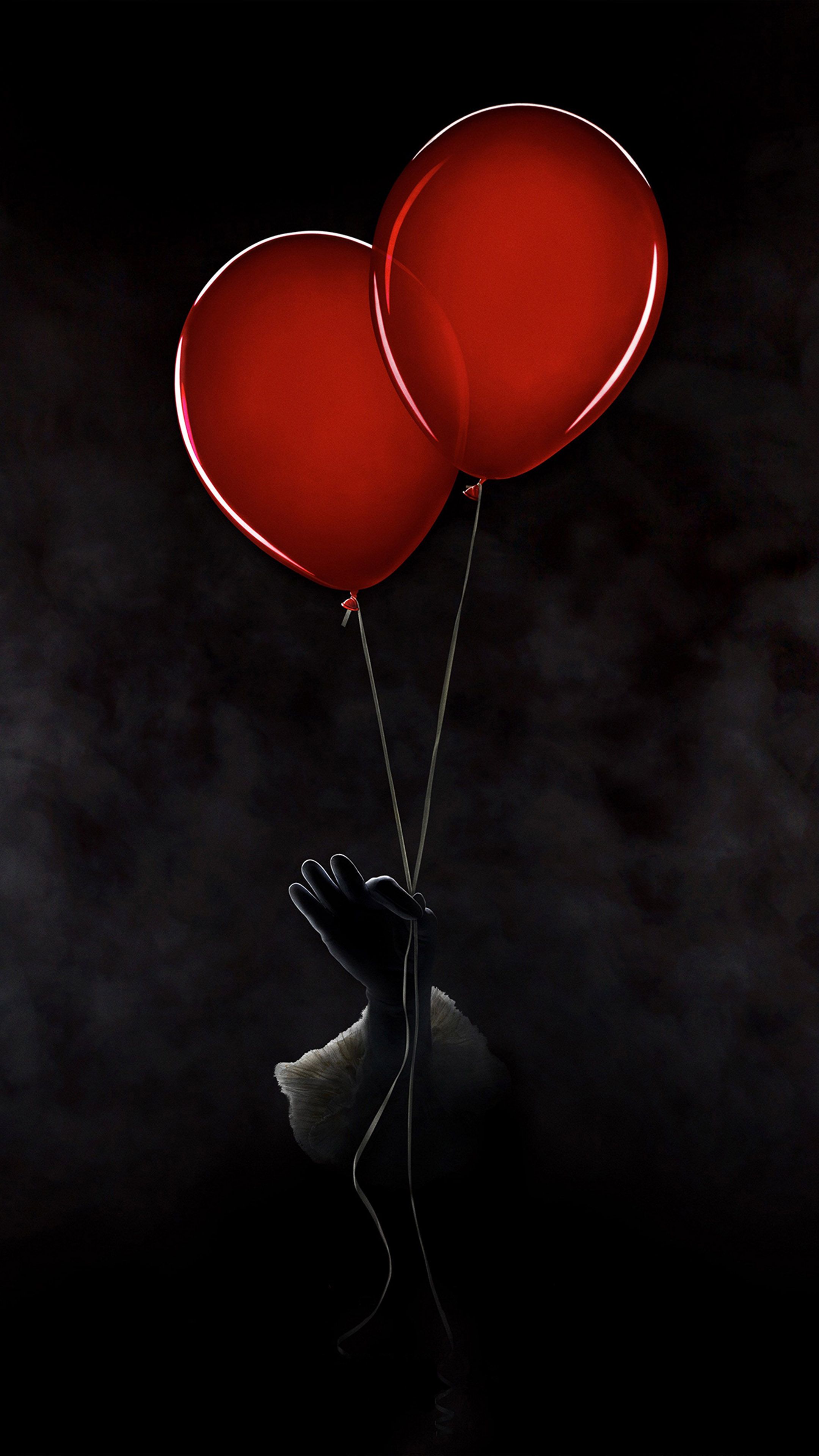 A hand wearing a black glove holding two red balloons - Balloons