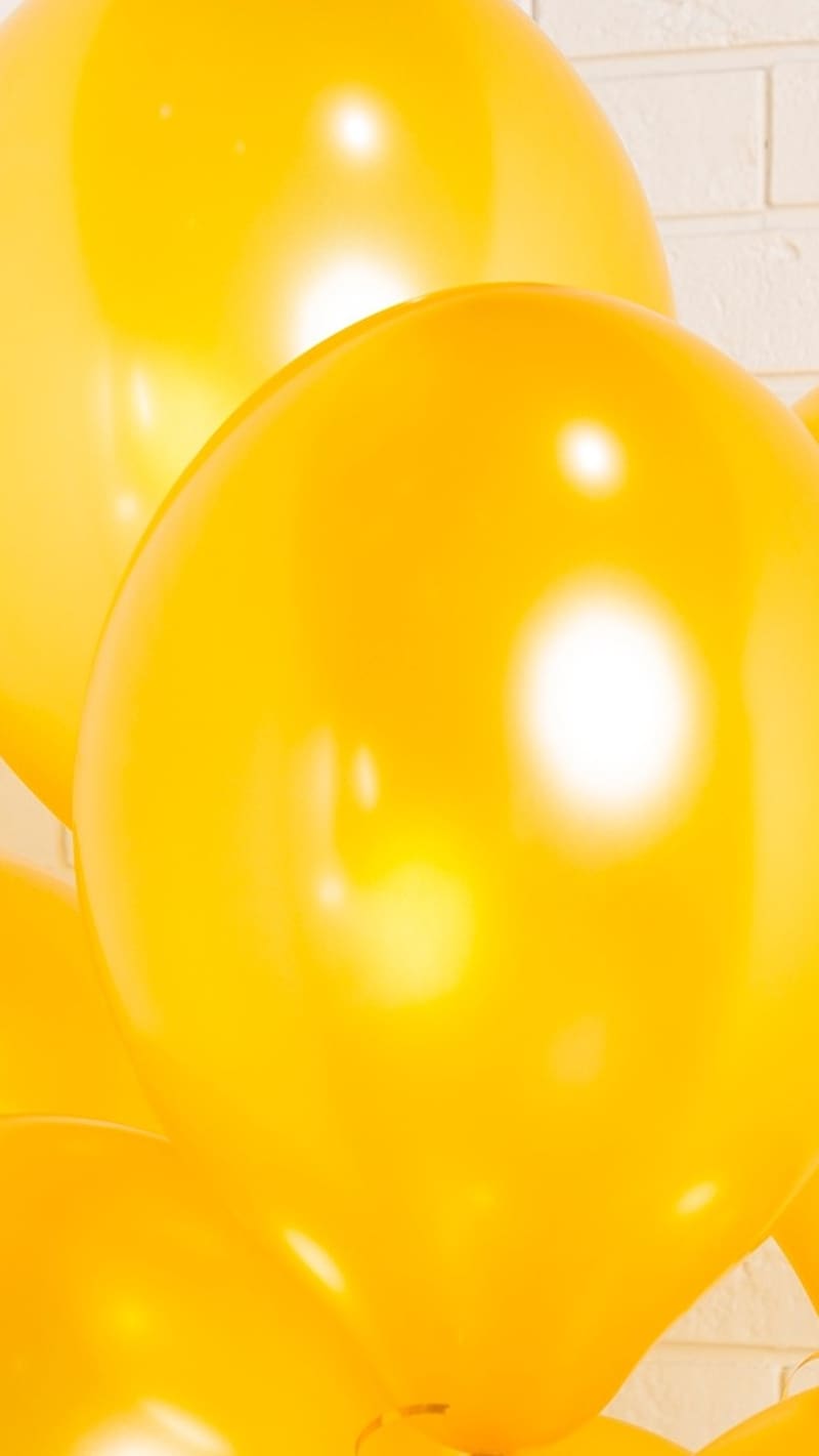 A bunch of yellow balloons are hanging from the ceiling - Balloons