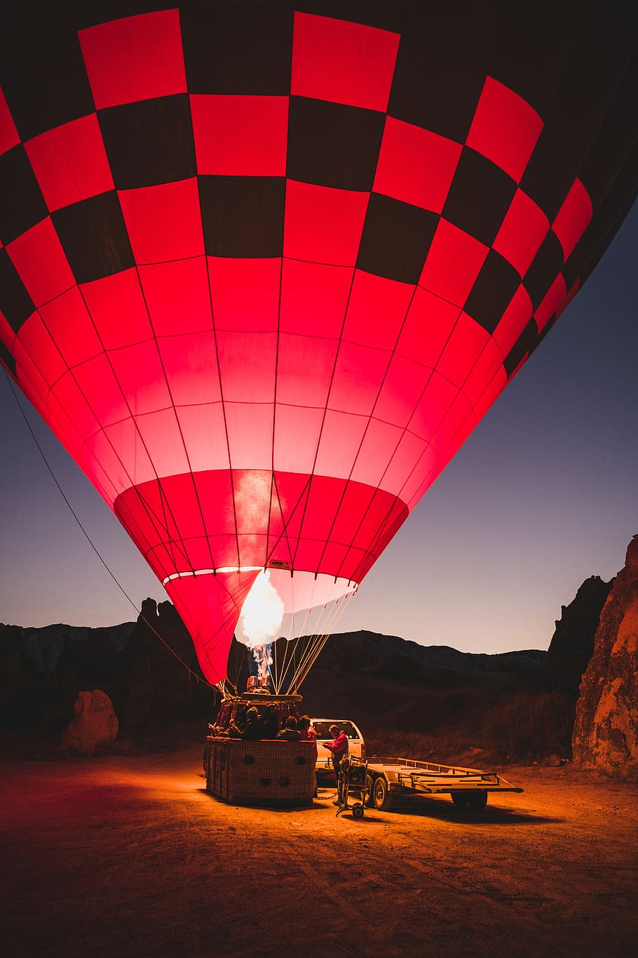 HD wallpaper: red and black hot air balloon on ground, person standing in between flatbed trailer and hot air balloon