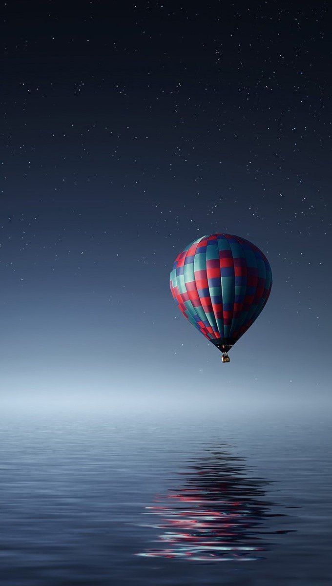 A hot air balloon flying over the water - Hot air balloons