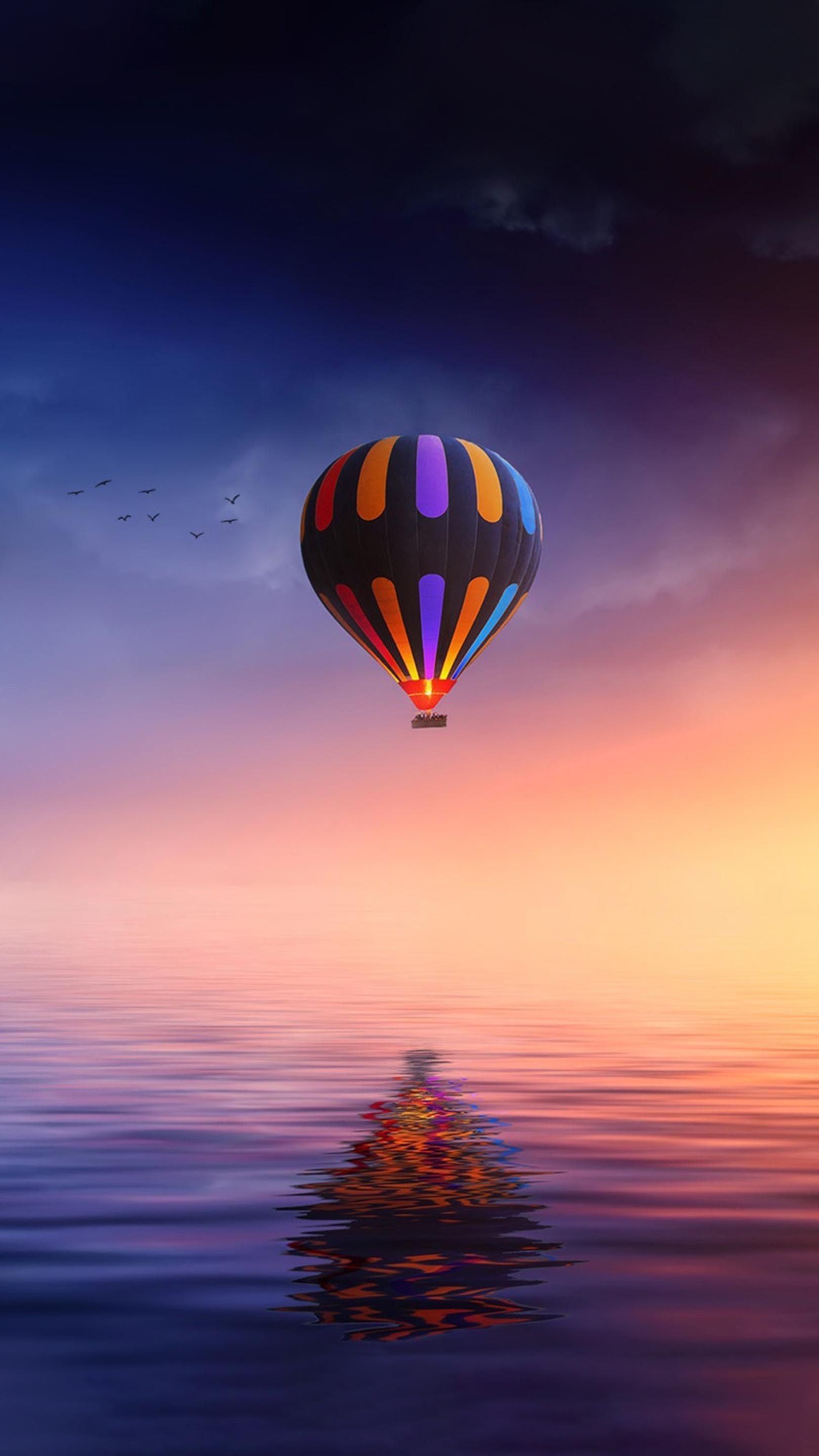 A colorful hot air balloon flying over the sea - Hot air balloons