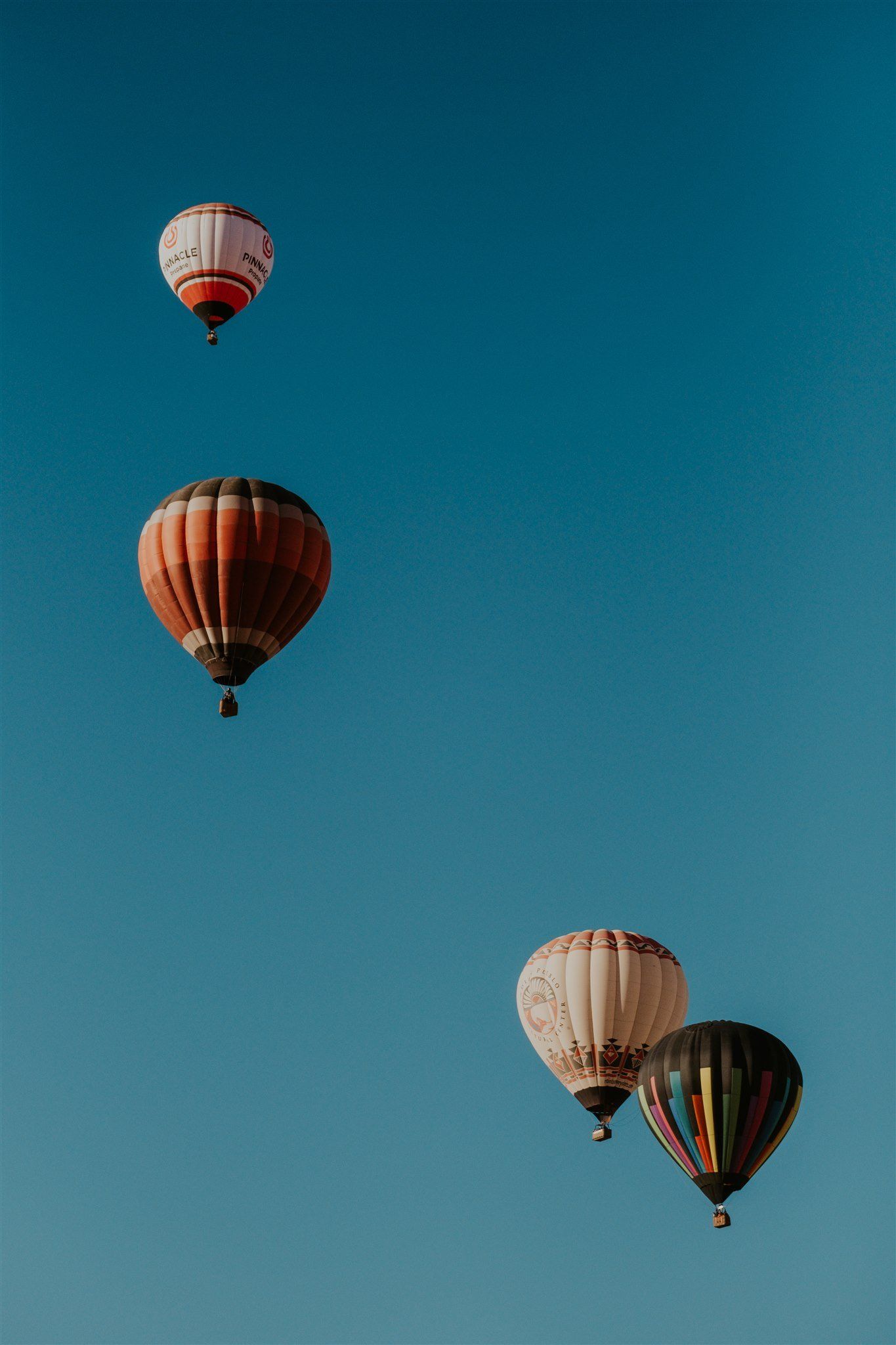 Four hot air balloons floating in a blue sky - Hot air balloons