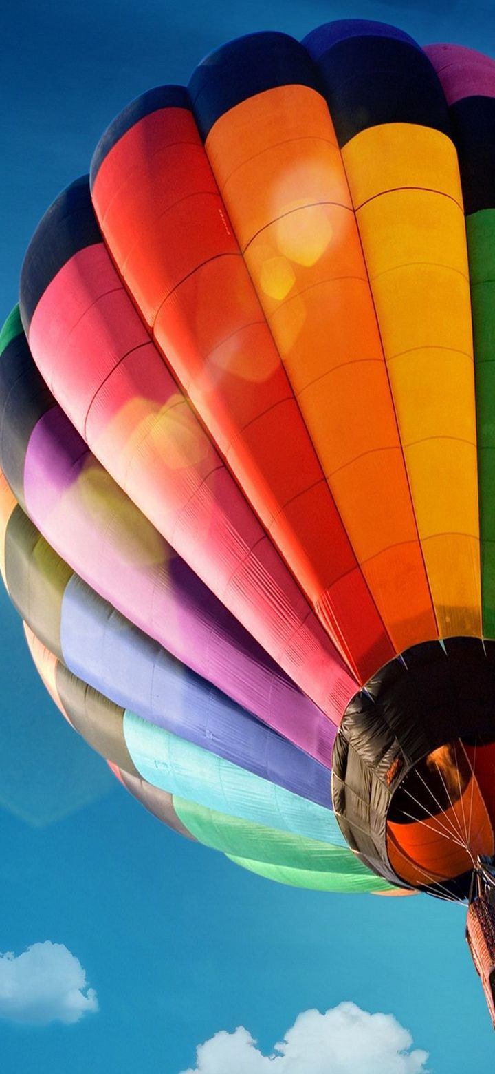 A colorful hot air balloon flying in the blue sky with clouds. Low angle shot. Bottom view. - Hot air balloons