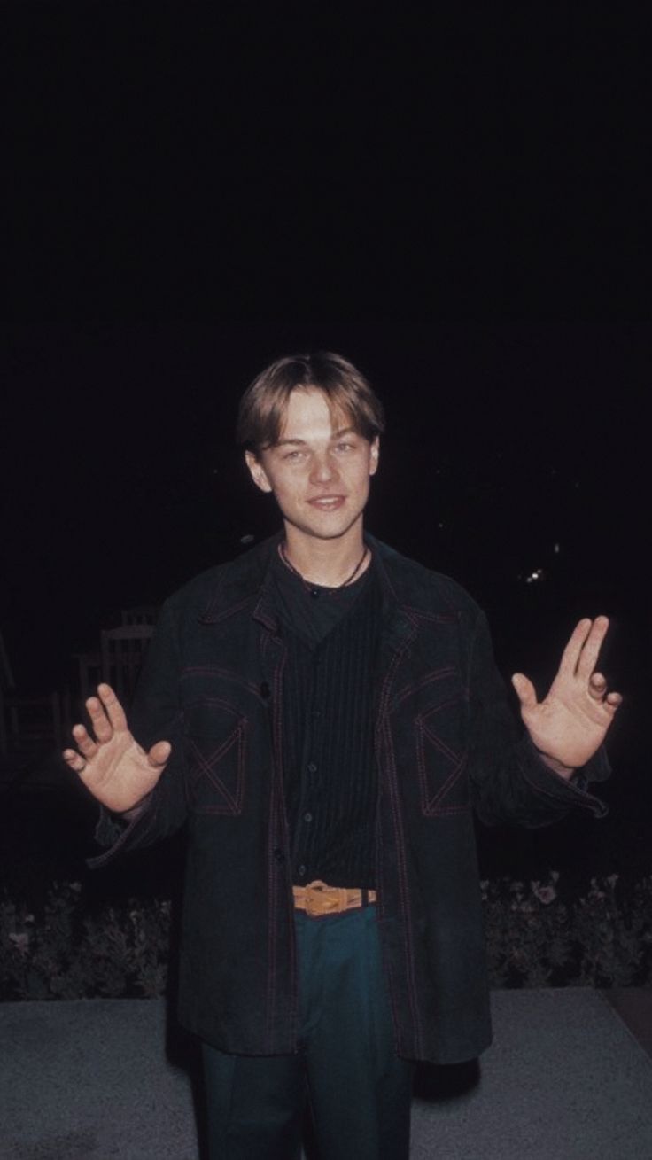 A man standing on the sidewalk with his hands up - Leonardo DiCaprio