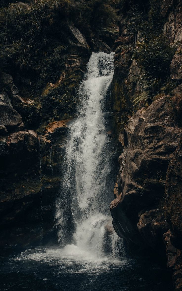 A waterfall cascading down rocks into a pool of water. - Waterfall