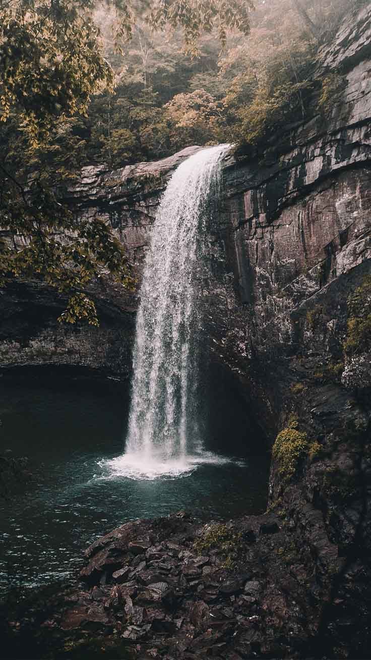 A waterfall surrounded by rocks and trees - Waterfall