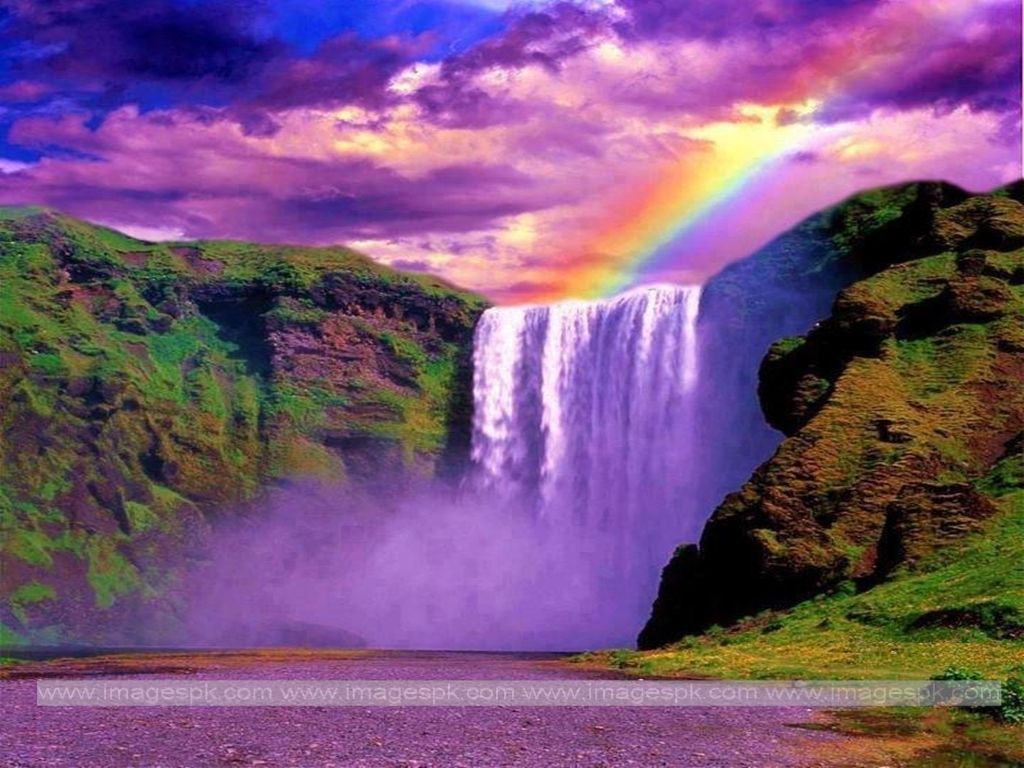 A rainbow over a waterfall in a mountain setting. - Waterfall