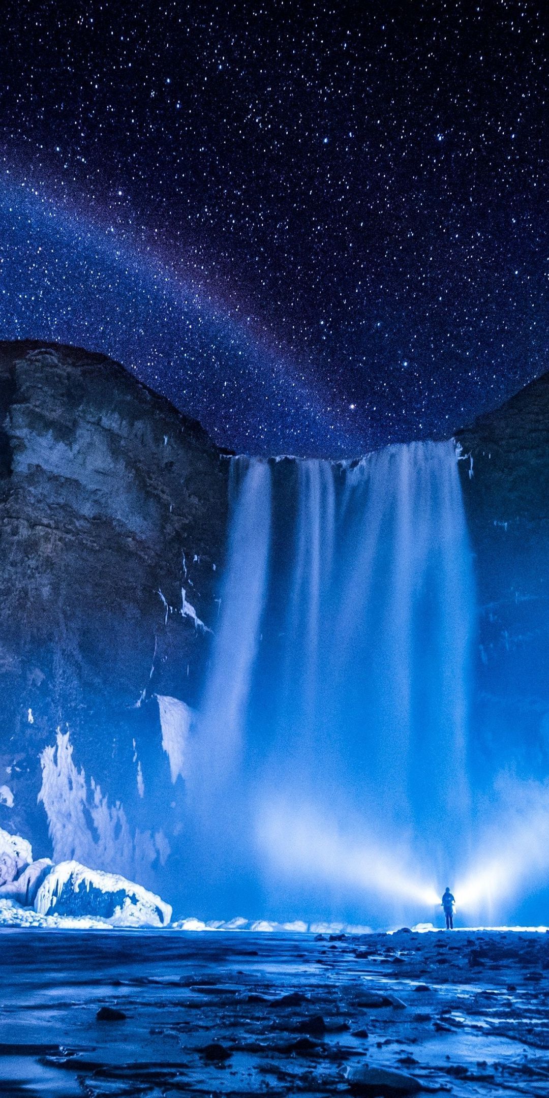 A man standing in front of an ice covered waterfall - Waterfall