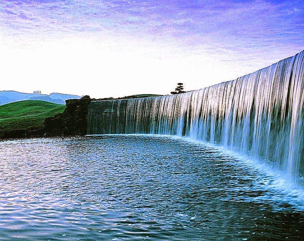 A waterfall in the middle of a green field - Waterfall