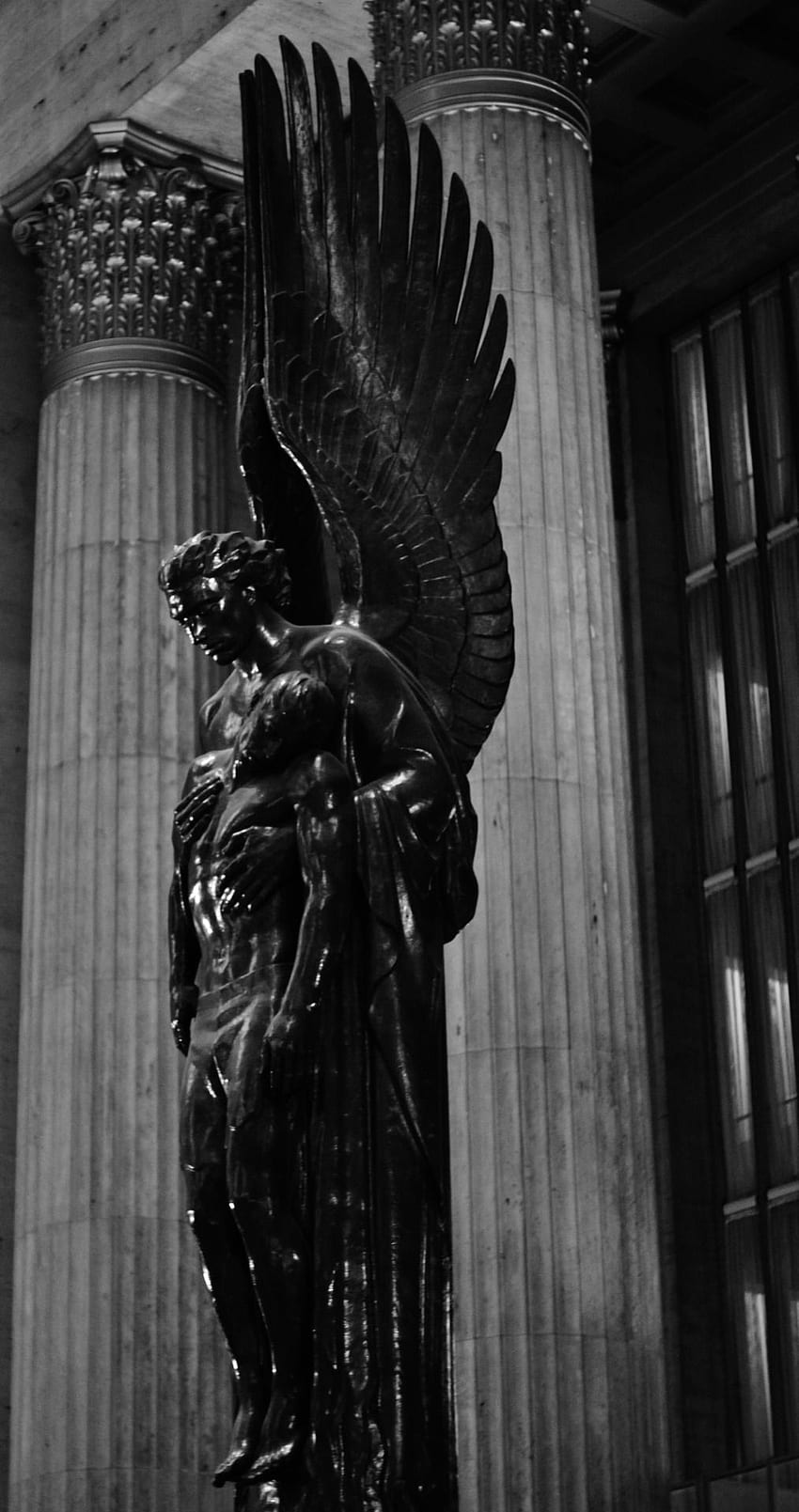 A statue of an angel in front of two columns. - Statue