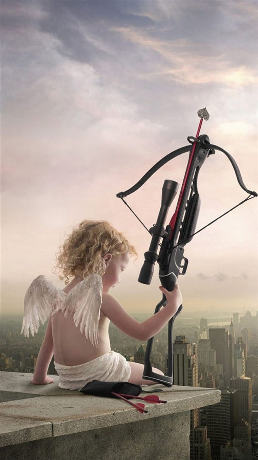 A child dressed as an angel sitting on a ledge holding a crossbow - Cupid