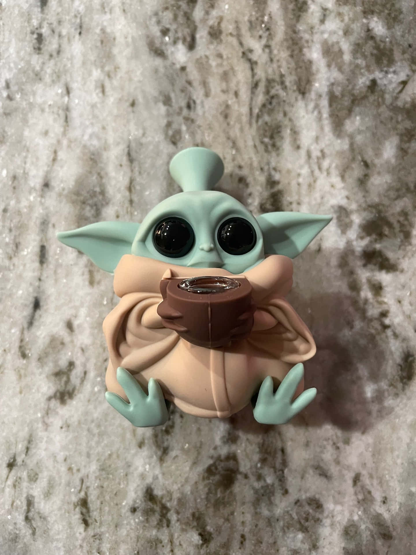 A baby yoda figurine is sitting on top of some rocks - Baby Yoda