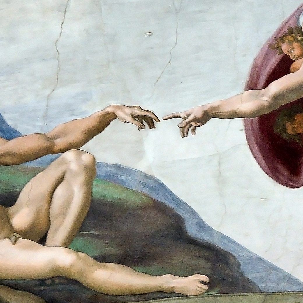 The ceiling of a painting showing two men holding hands - The Creation of Adam