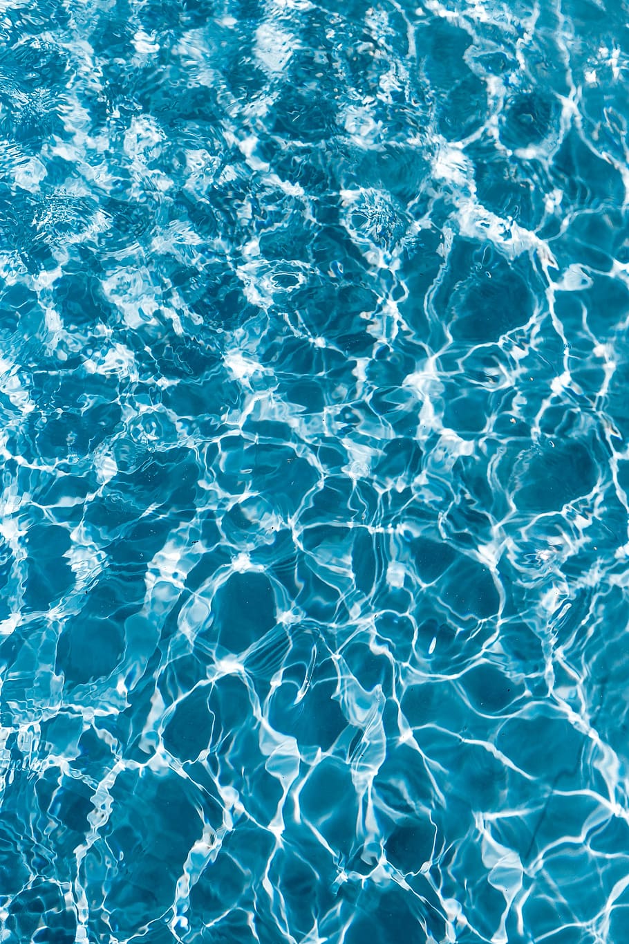 Blue water in a pool with light reflecting off the surface - Swimming pool