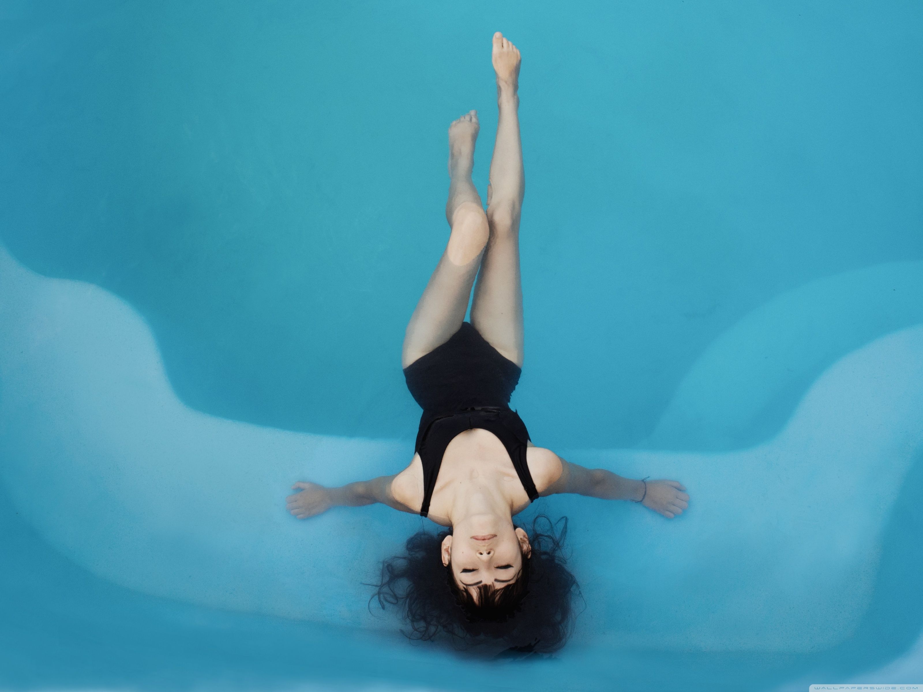 A woman in black swimsuit floating on her back - Swimming pool