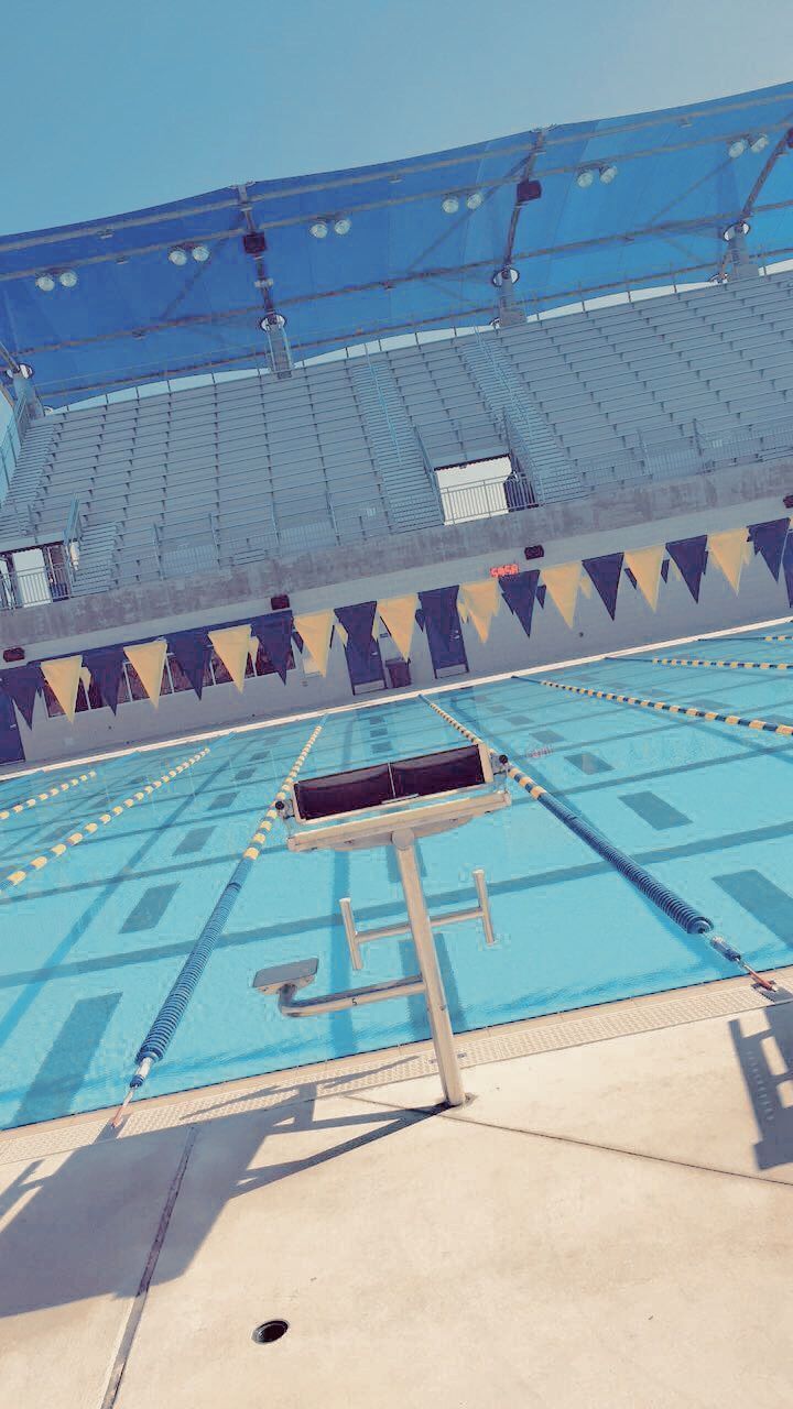 Swimming pool with blue water and flags lining the pool. - Swimming pool