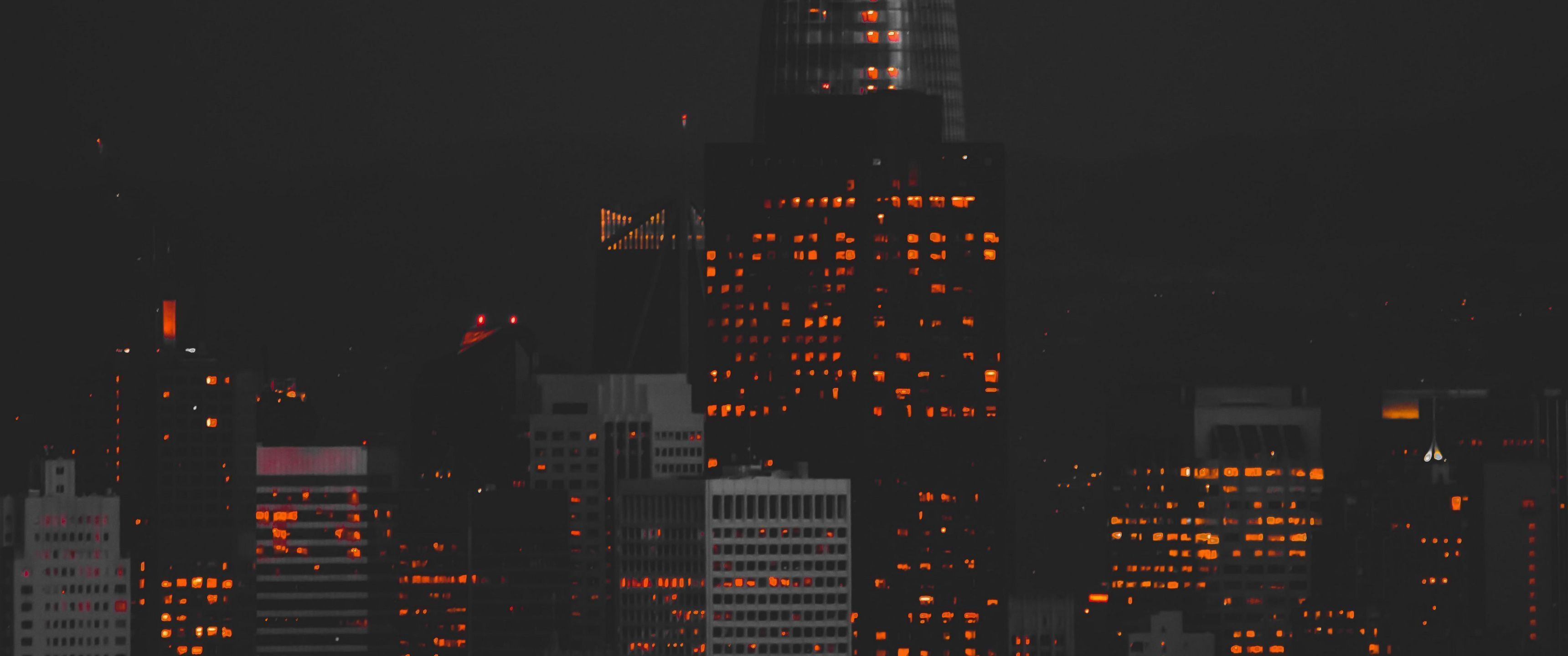A city skyline at night with the buildings lit up - 3440x1440
