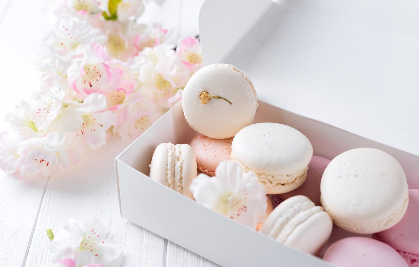 A box of macarons with flowers on the side. - Macarons