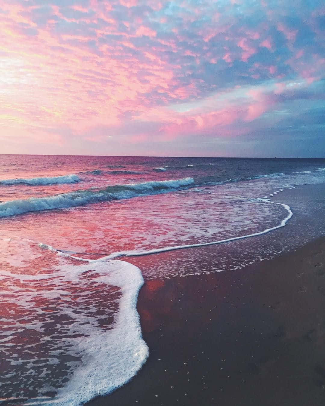 A beautiful sunset over the ocean with pink and purple hues. - Coast
