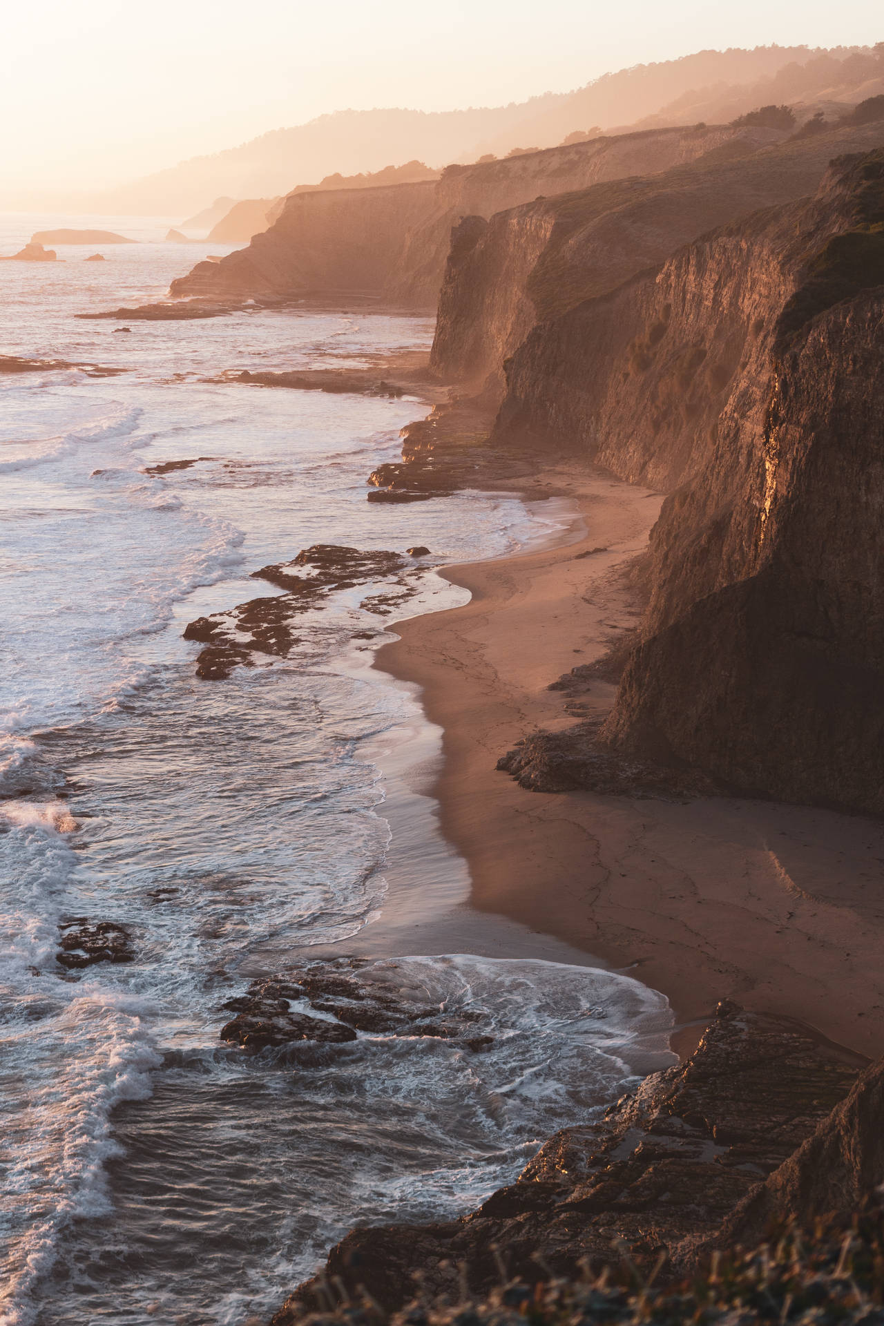 A photo of the ocean meeting the cliffs at sunset - Coast