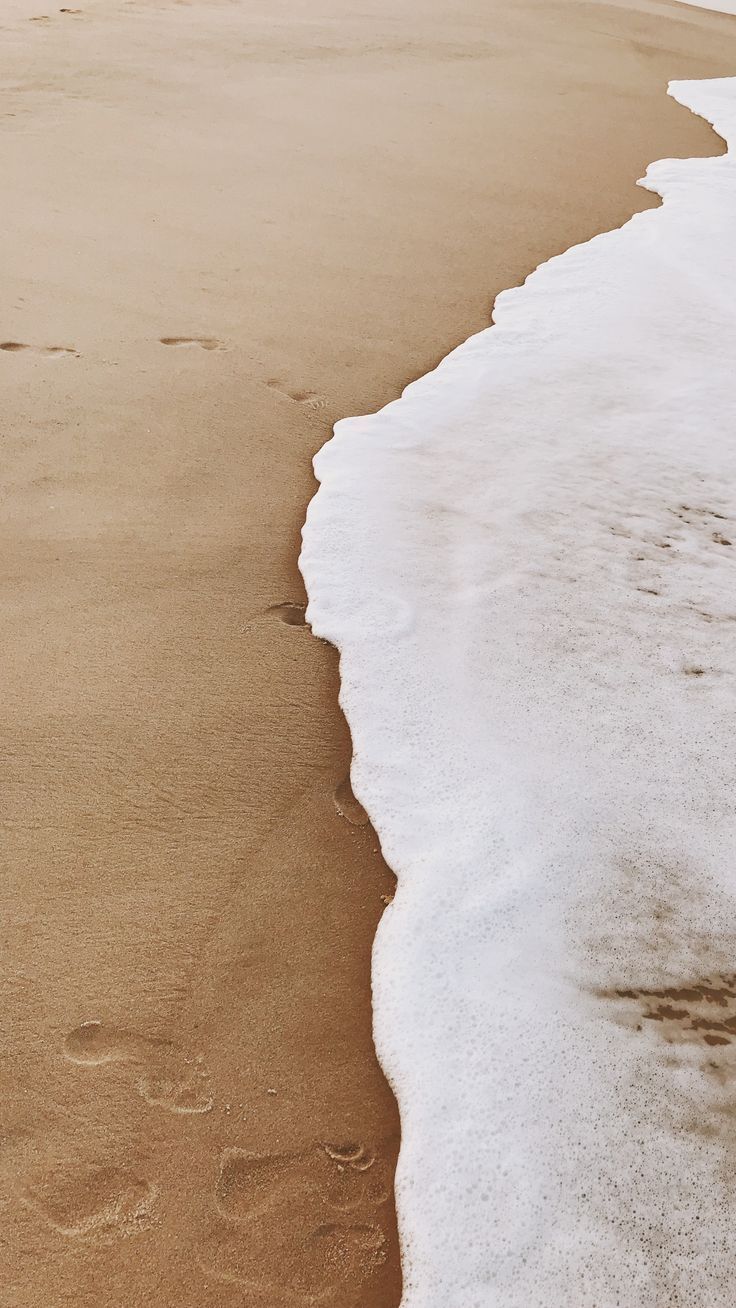 A wave is coming in and leaving footprints in the sand. - Coast