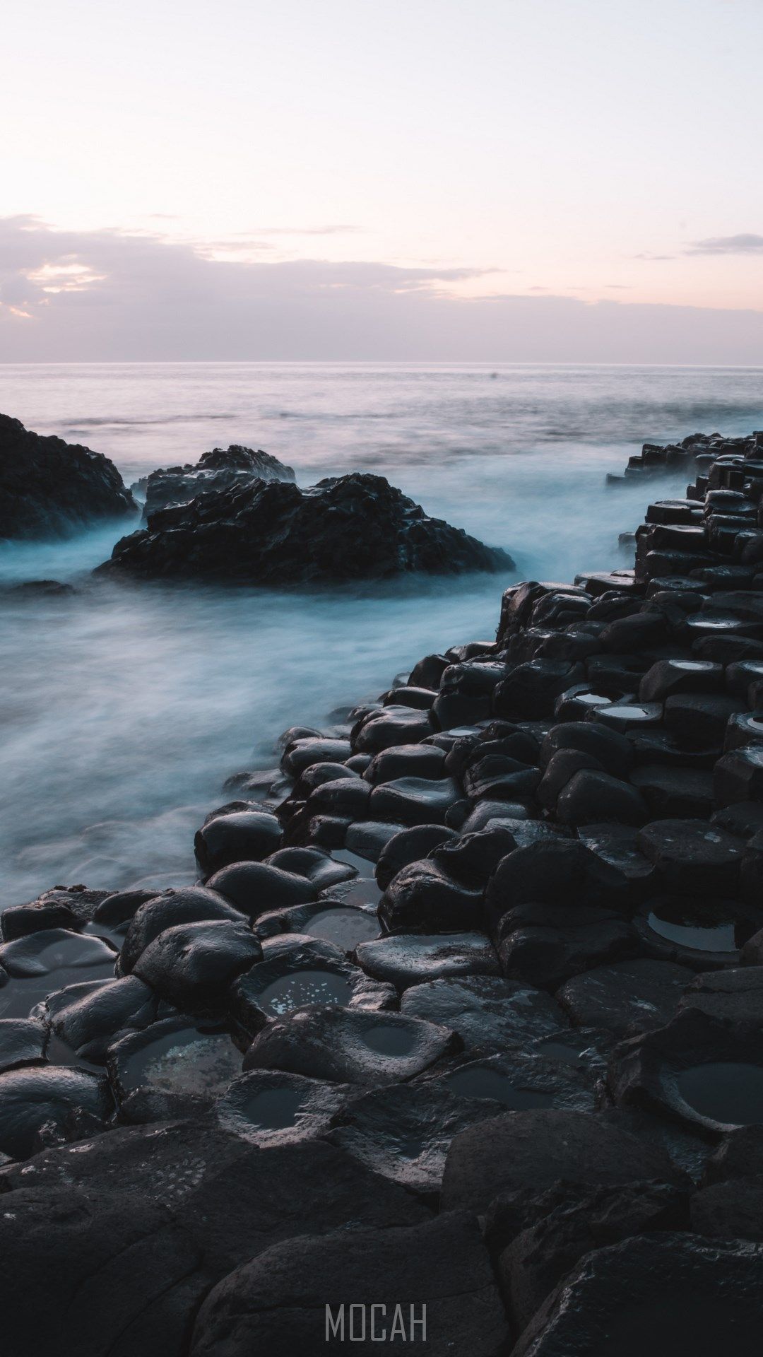 The ocean is at sunset and there are rocks on it - Coast