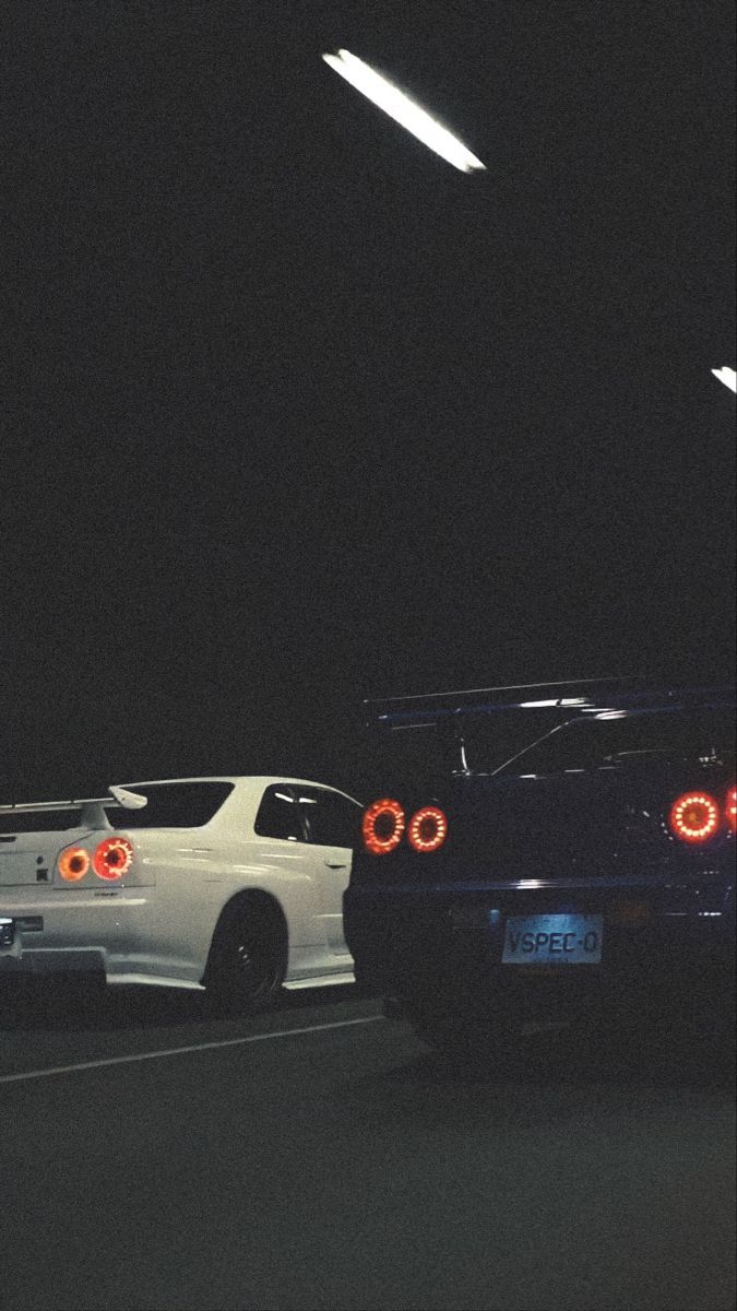 A couple of cars driving down the street - Nissan Skyline, JDM