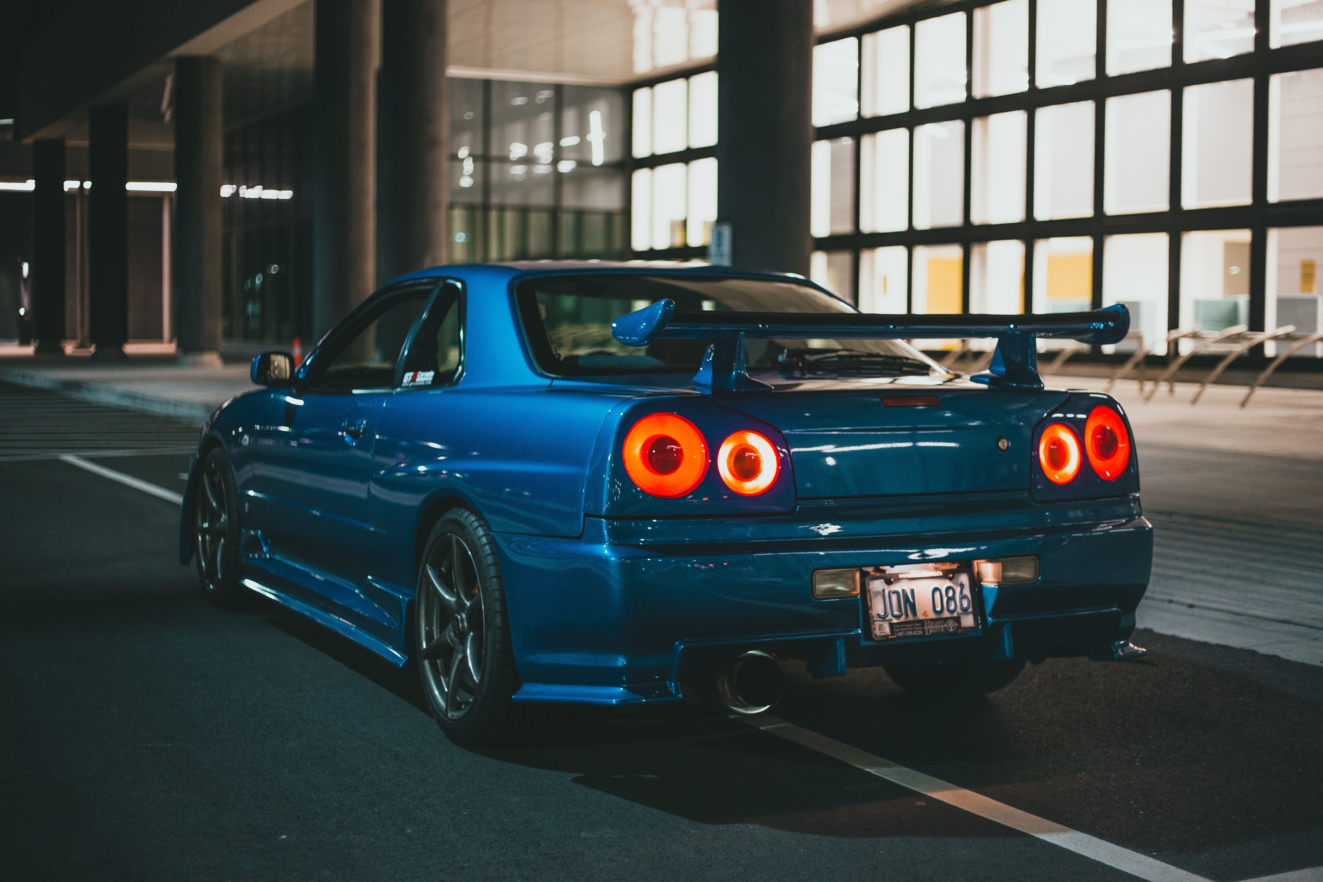 A blue car parked in the middle of an empty parking lot - Nissan Skyline