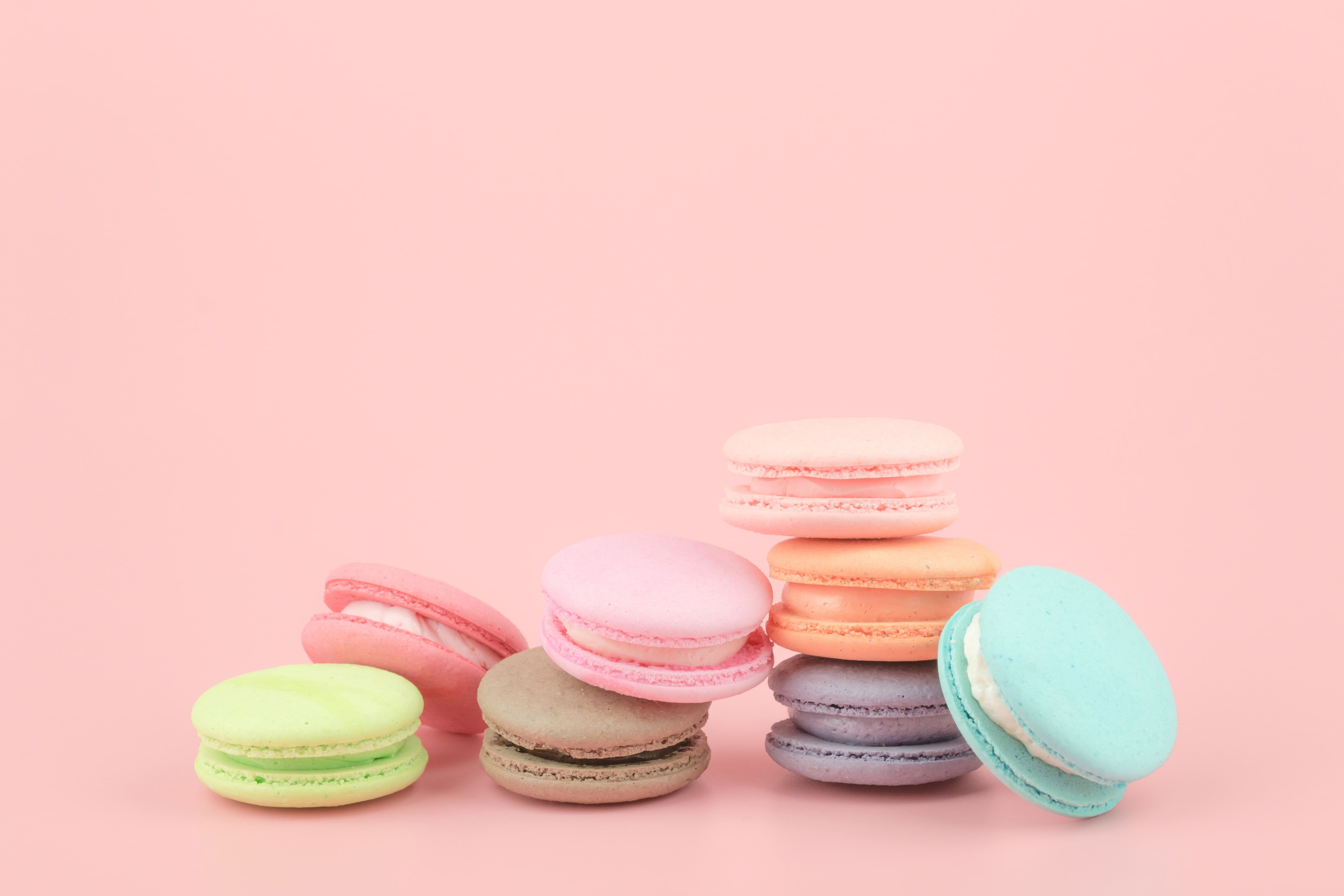 A pile of seven macarons in varying shades of pink, blue, and green. - Macarons