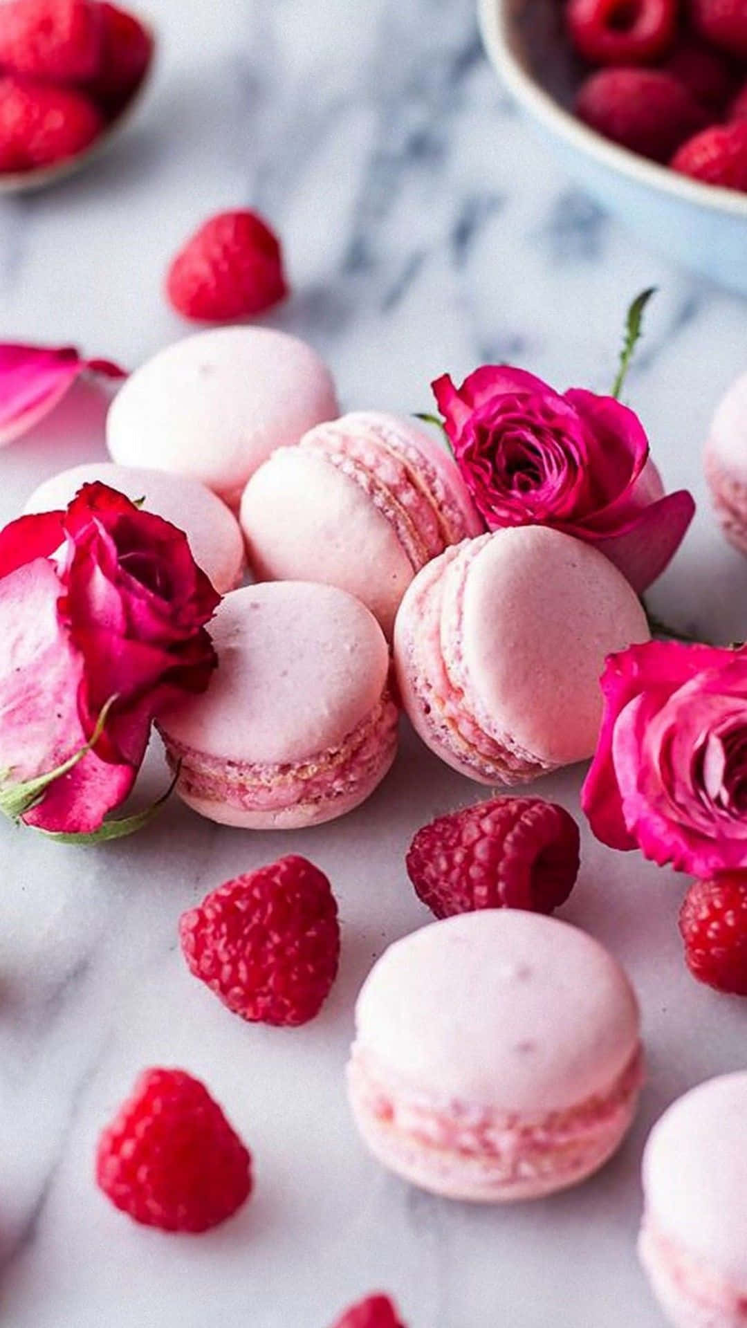 Raspberry macarons, raspberries and roses on a marble table. - Macarons