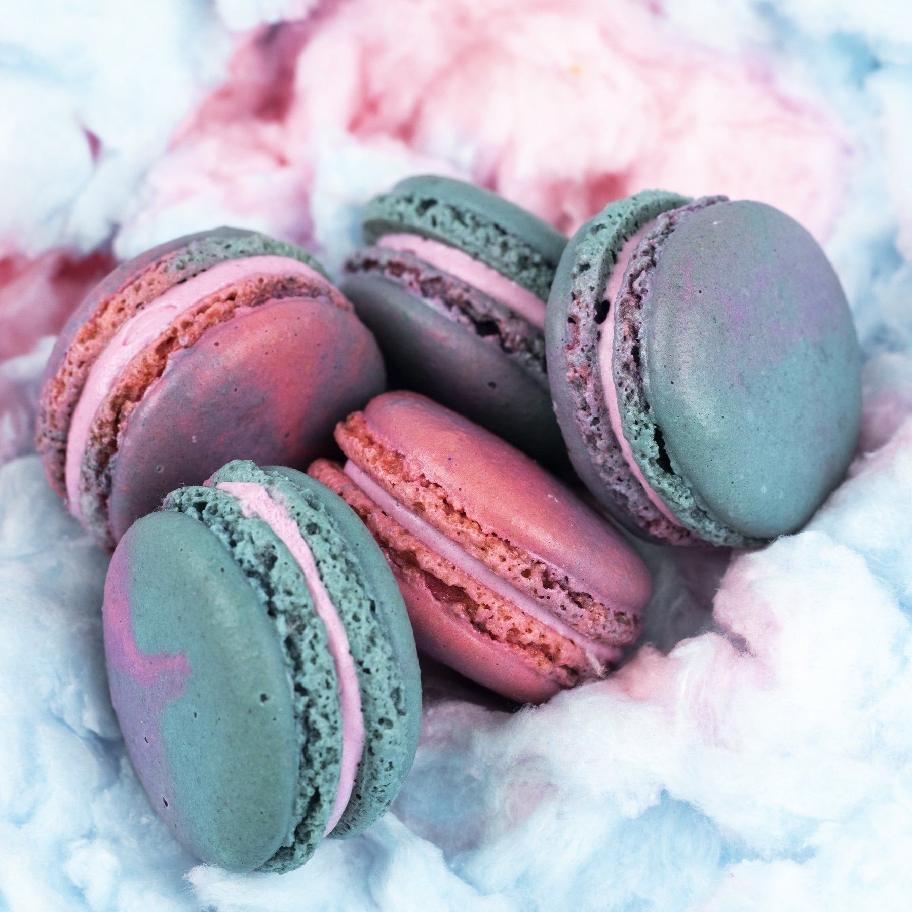 A plate of blue and pink macarons with a cotton candy background - Macarons