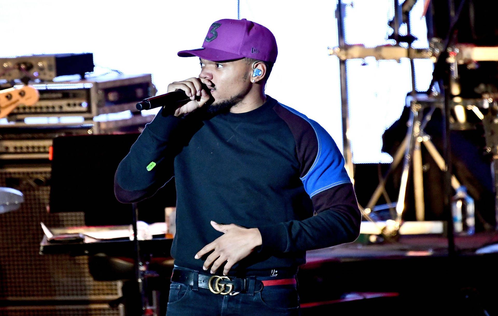 A man in black and purple clothing singing into microphone - Chance the Rapper