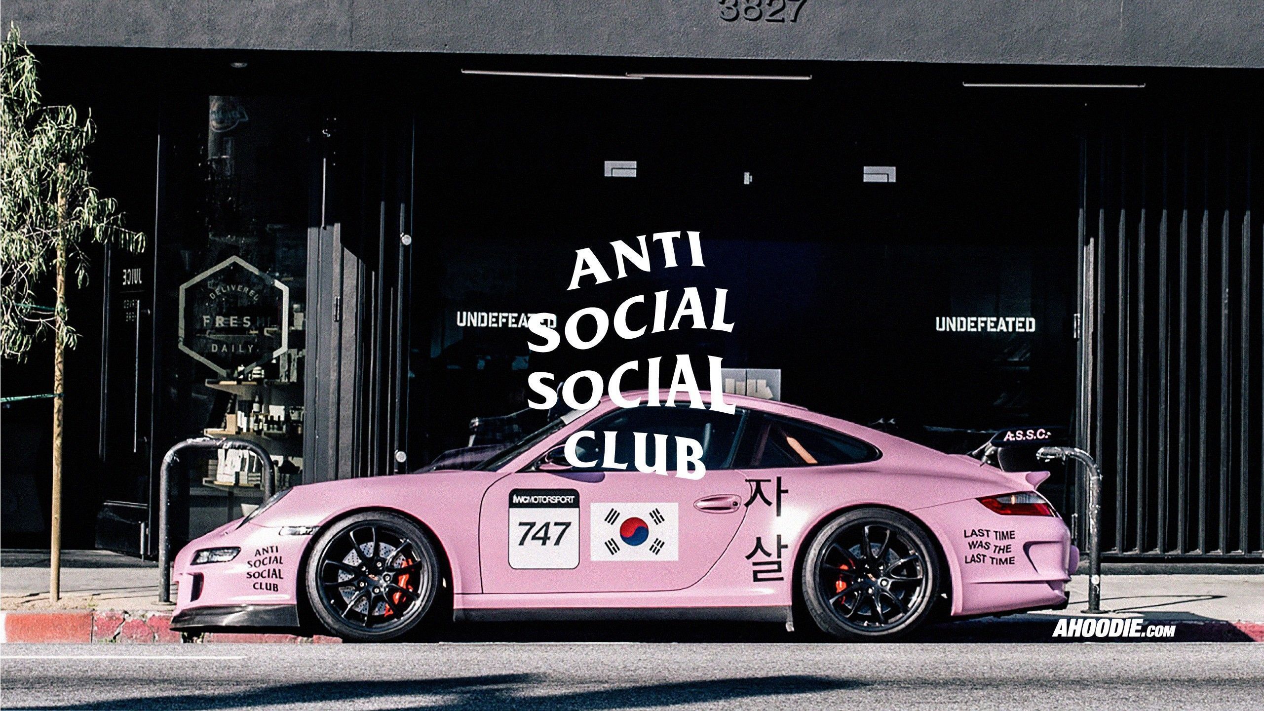 A pink Porsche 911 GT3 parked in front of an Anti Social Social Club store - Anti Social Social Club
