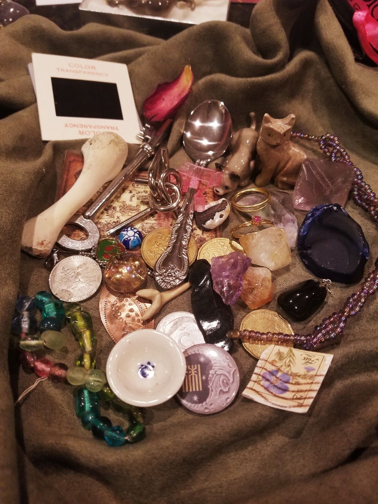 A collection of various items including coins, spoons, beads, and a carved bone. - Witchcore