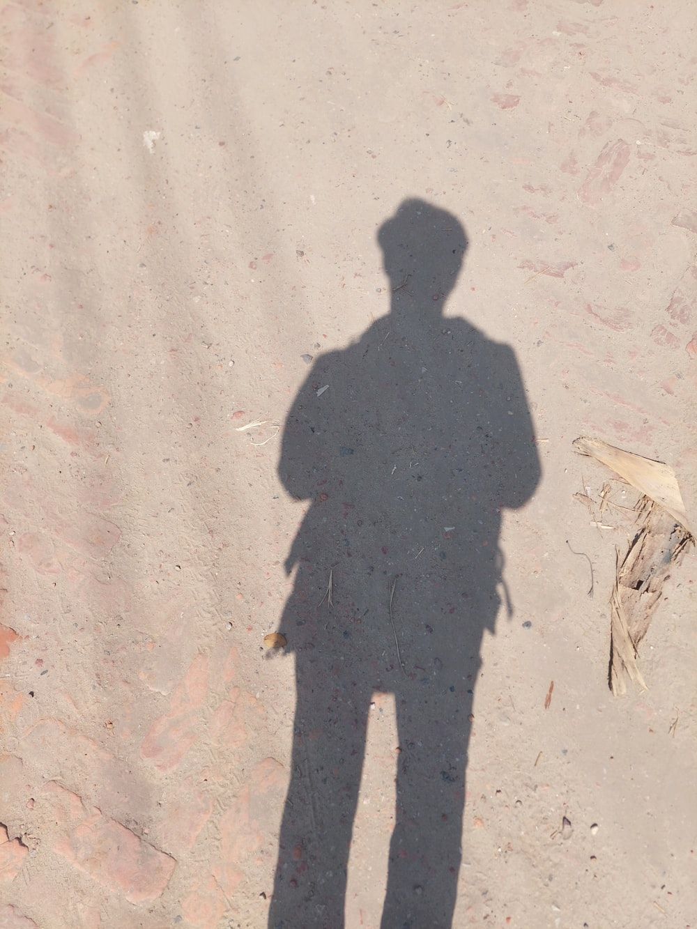 A shadow of a person standing in the dirt photo