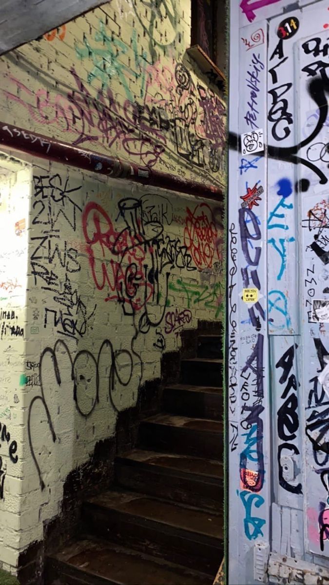 Stairs covered in graffiti, with the walls and a doorpost also covered in graffiti. - Street art