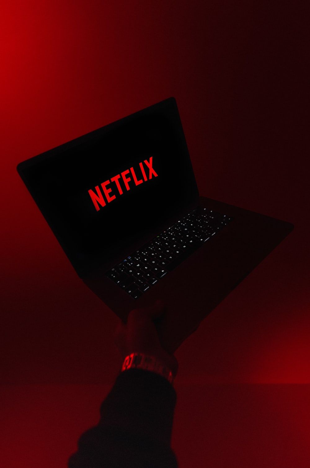 A person holding up an open laptop - Netflix
